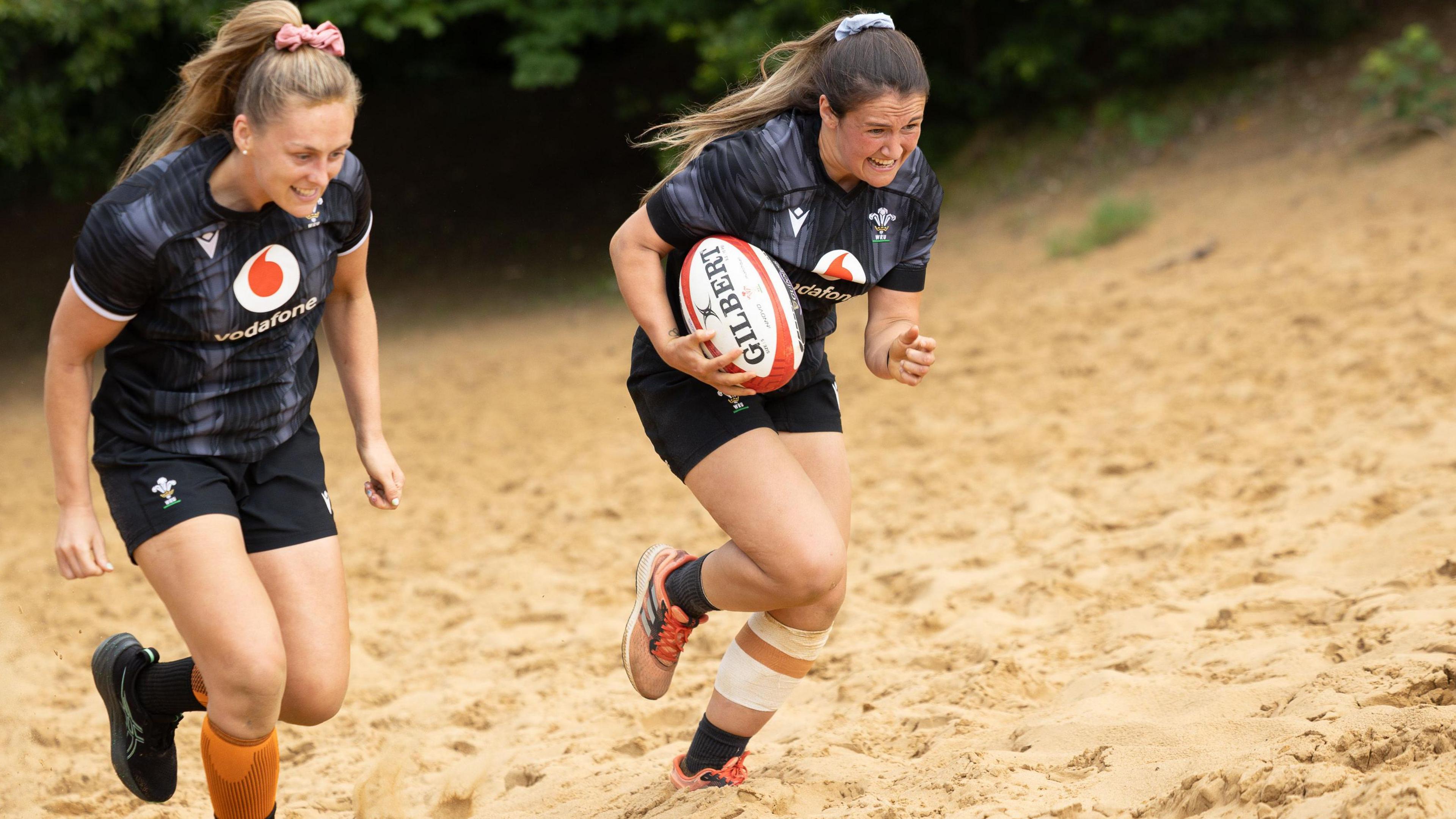 Hannah Jones and Kayleigh Powell running up a sand dune