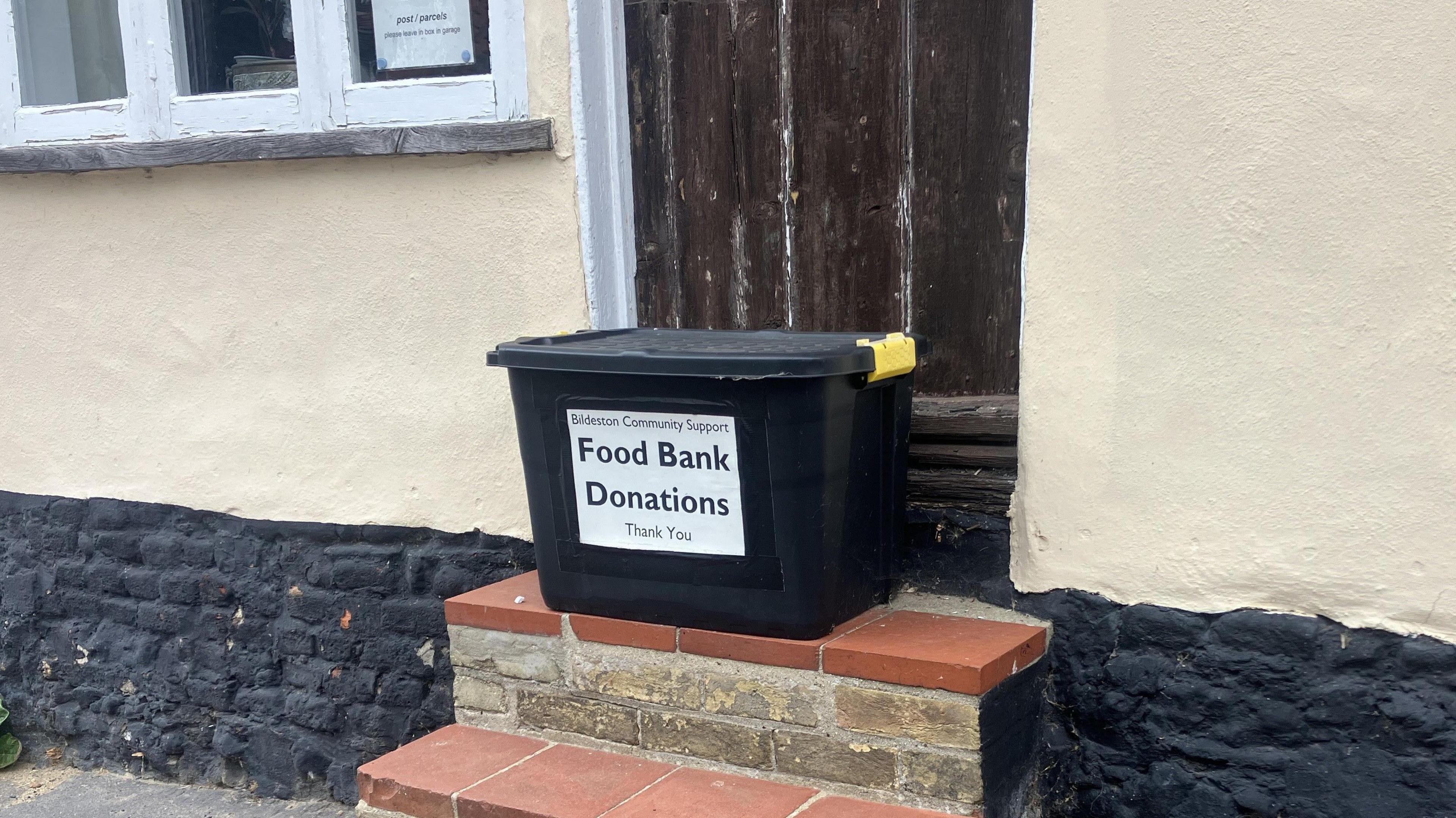 A foodbank donation box sits on the steps of the foodbank. 