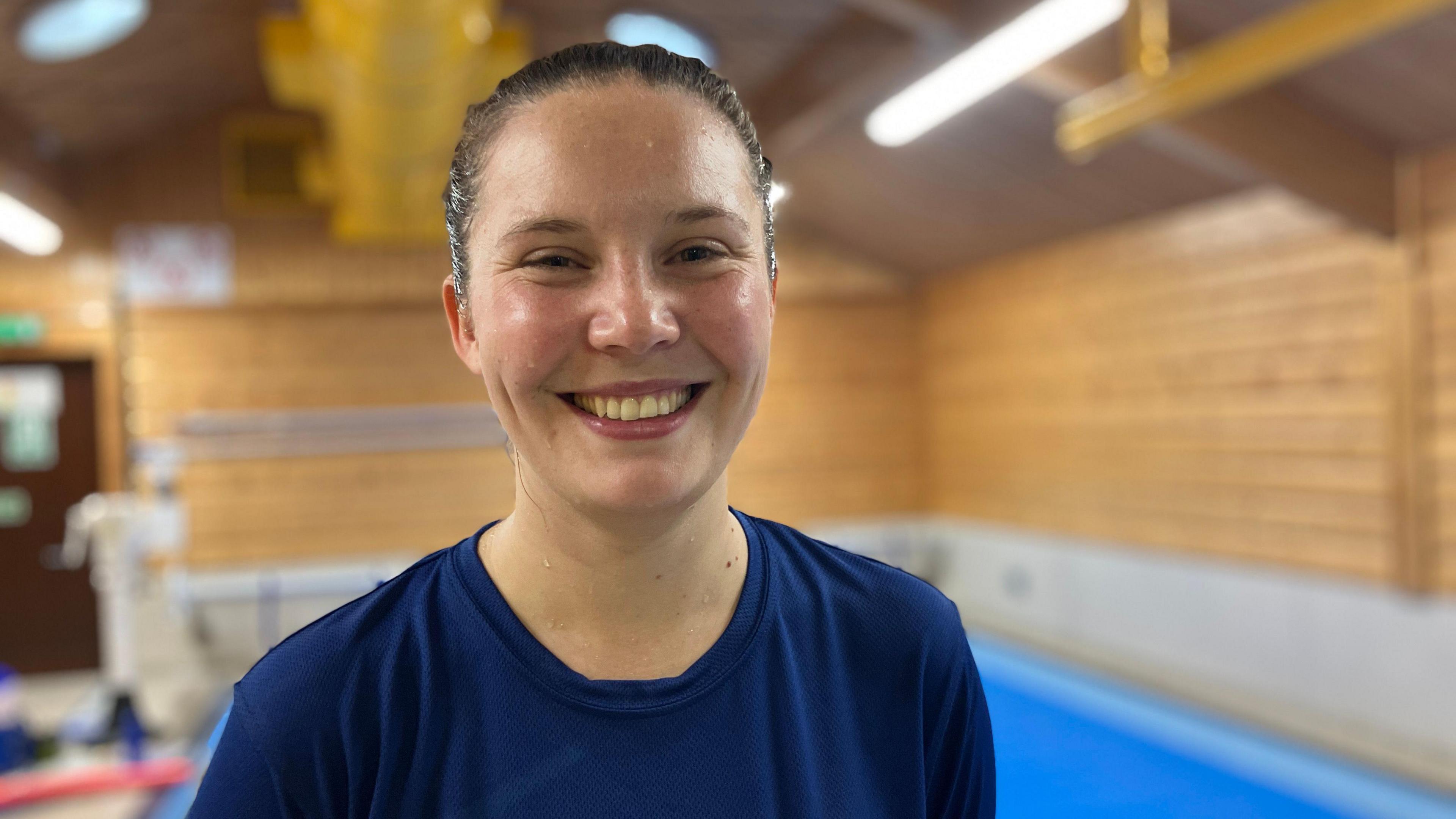 Jeny Johnson who co-founded NOVA Sports smiling into the camera whilst standing in front of the pool