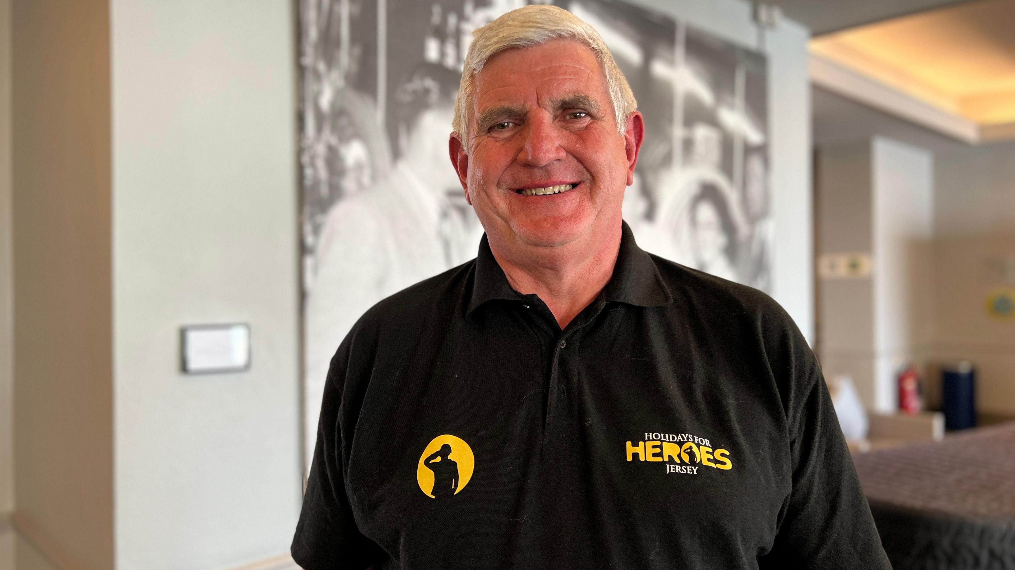 Richard Woodhouse smiles at the camera wearing a Holidays for Heroes top