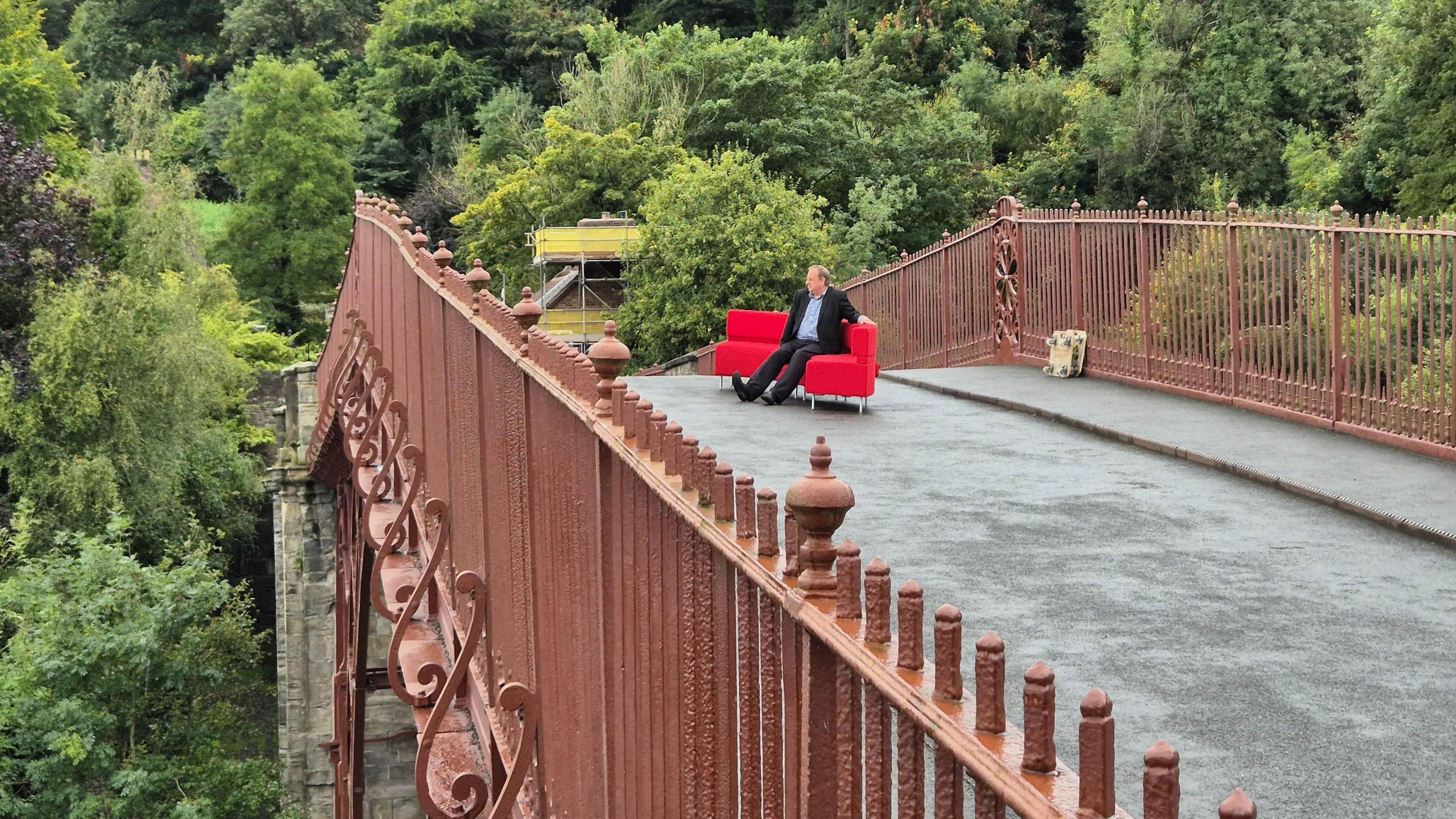 Reporter Ben Sidwell sits on the red sofa on the famous Iron Bridge in Shropshire 