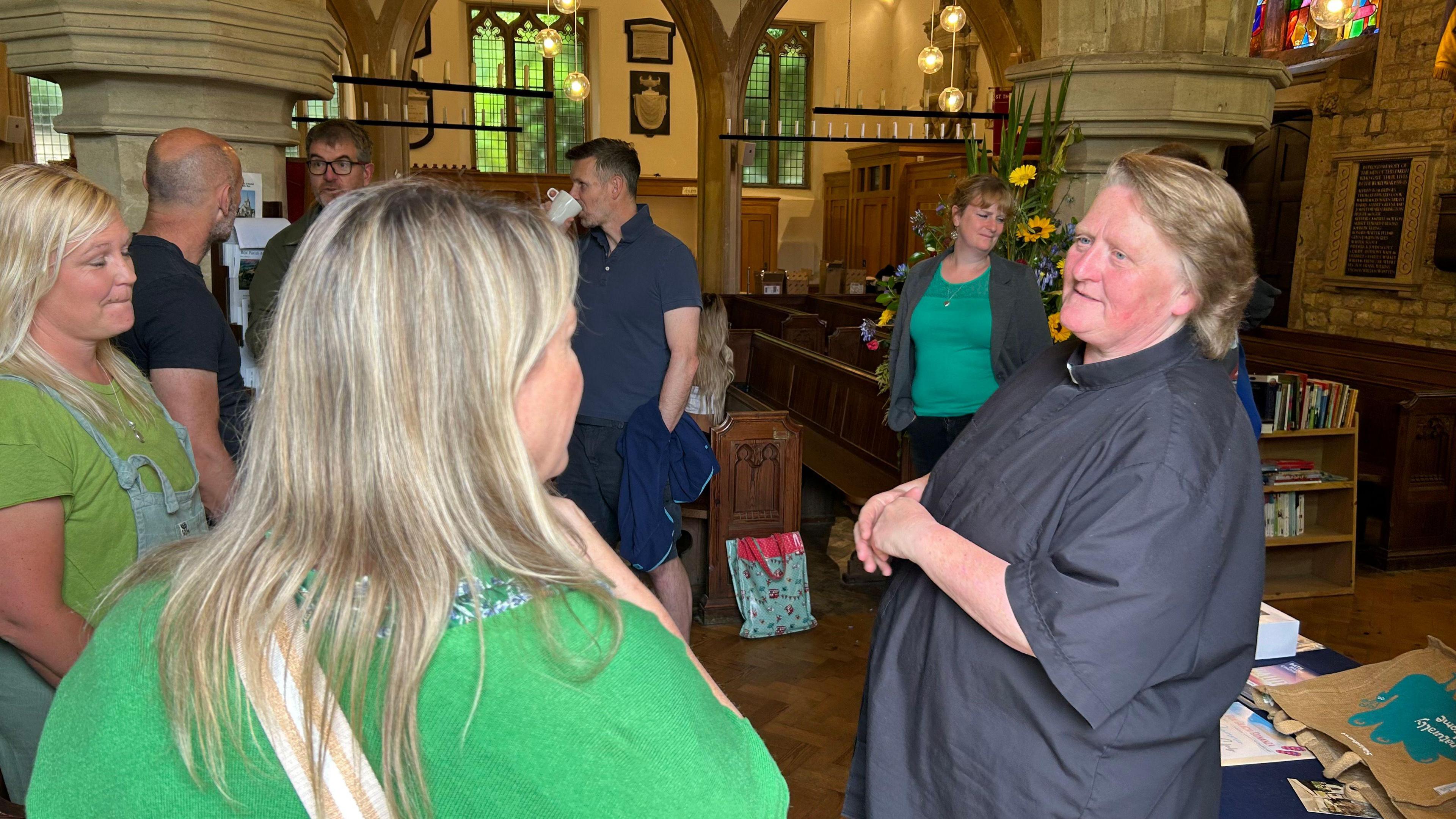 Clair Southgate talking to members of the congregation inside a church