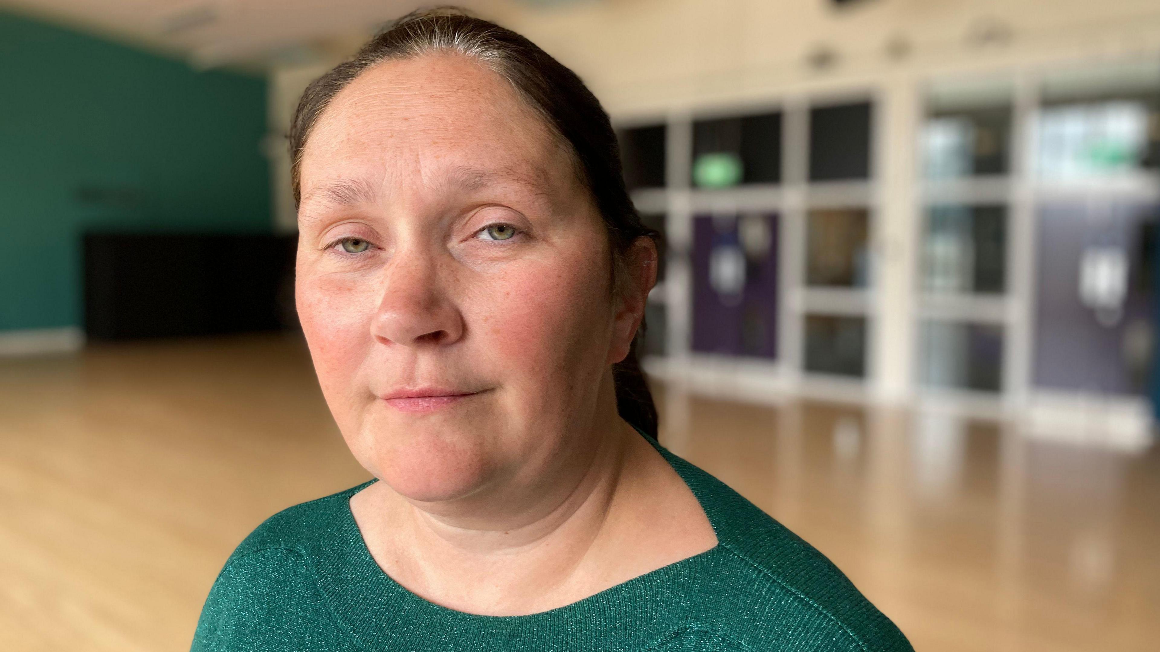 Detective Chief Superintendent Lindsay Fisher staring at the camera. Her hair is pulled back into a ponytail and she is wearing a green jumper