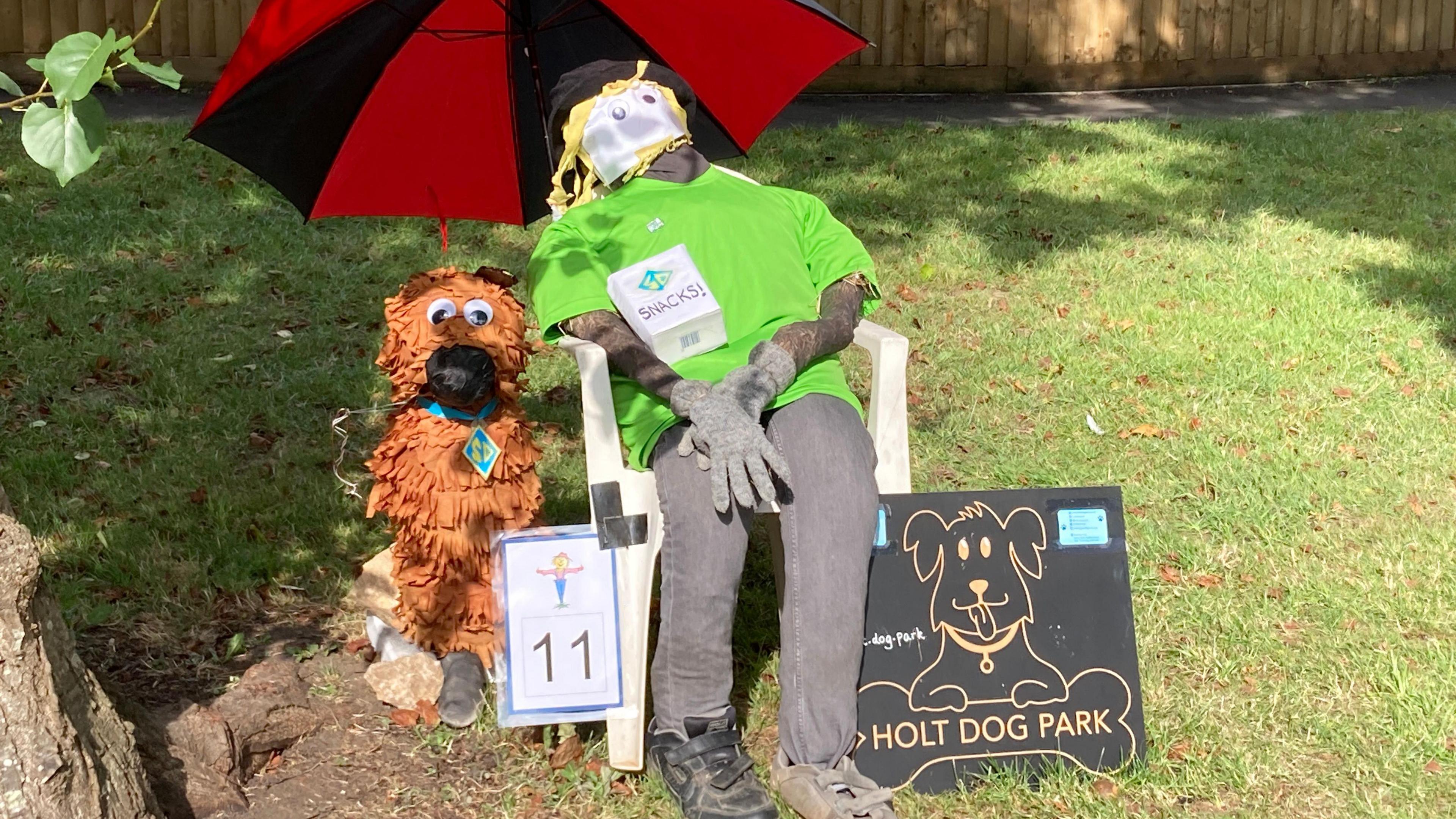 A scarecrow of Shaggy sitting on a white plastic garden chair with Scooby Doo