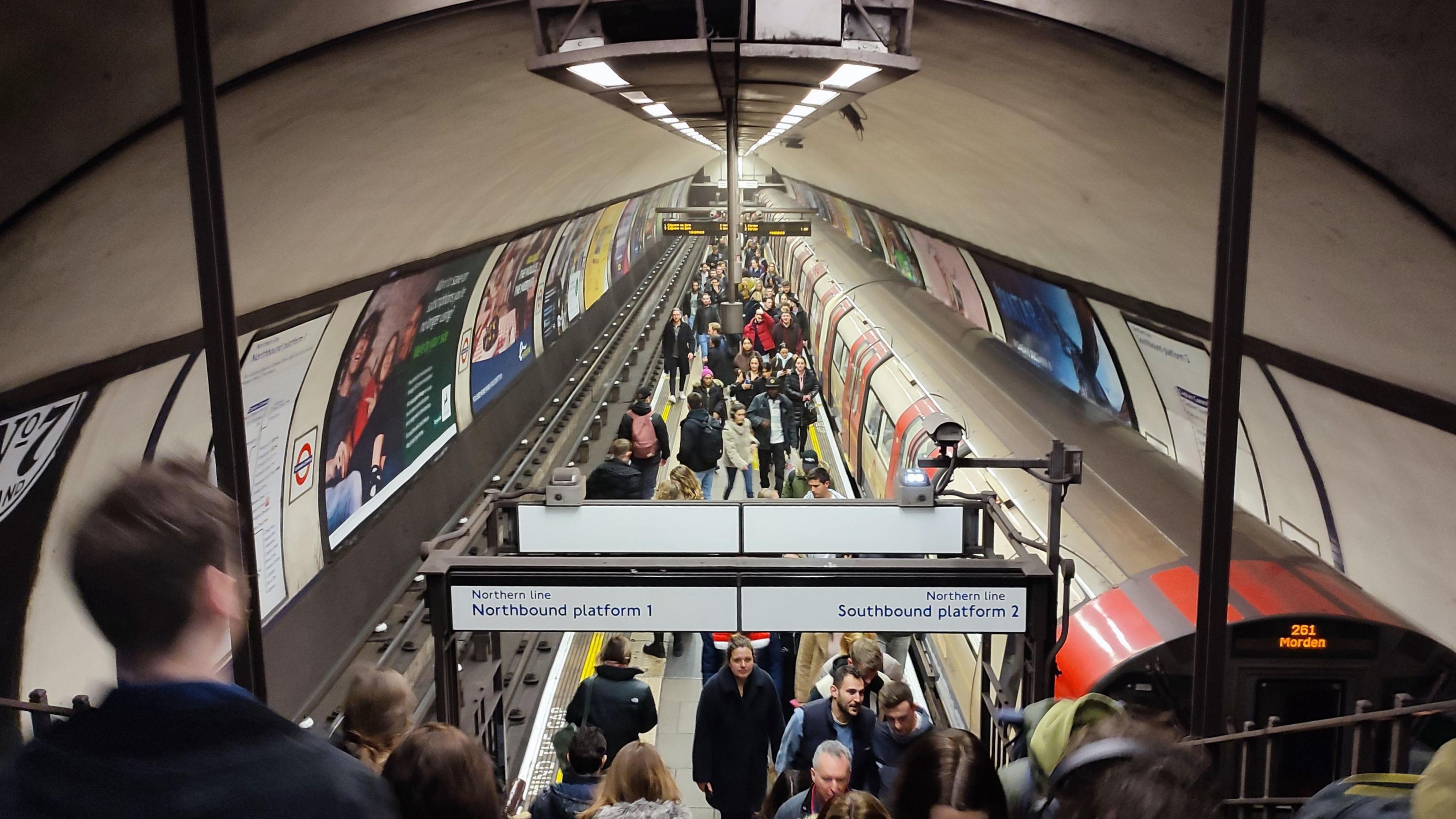 Stock image of passengers getting off a London Underground tube train onto the island narrow platform at Clapham Common tube station.