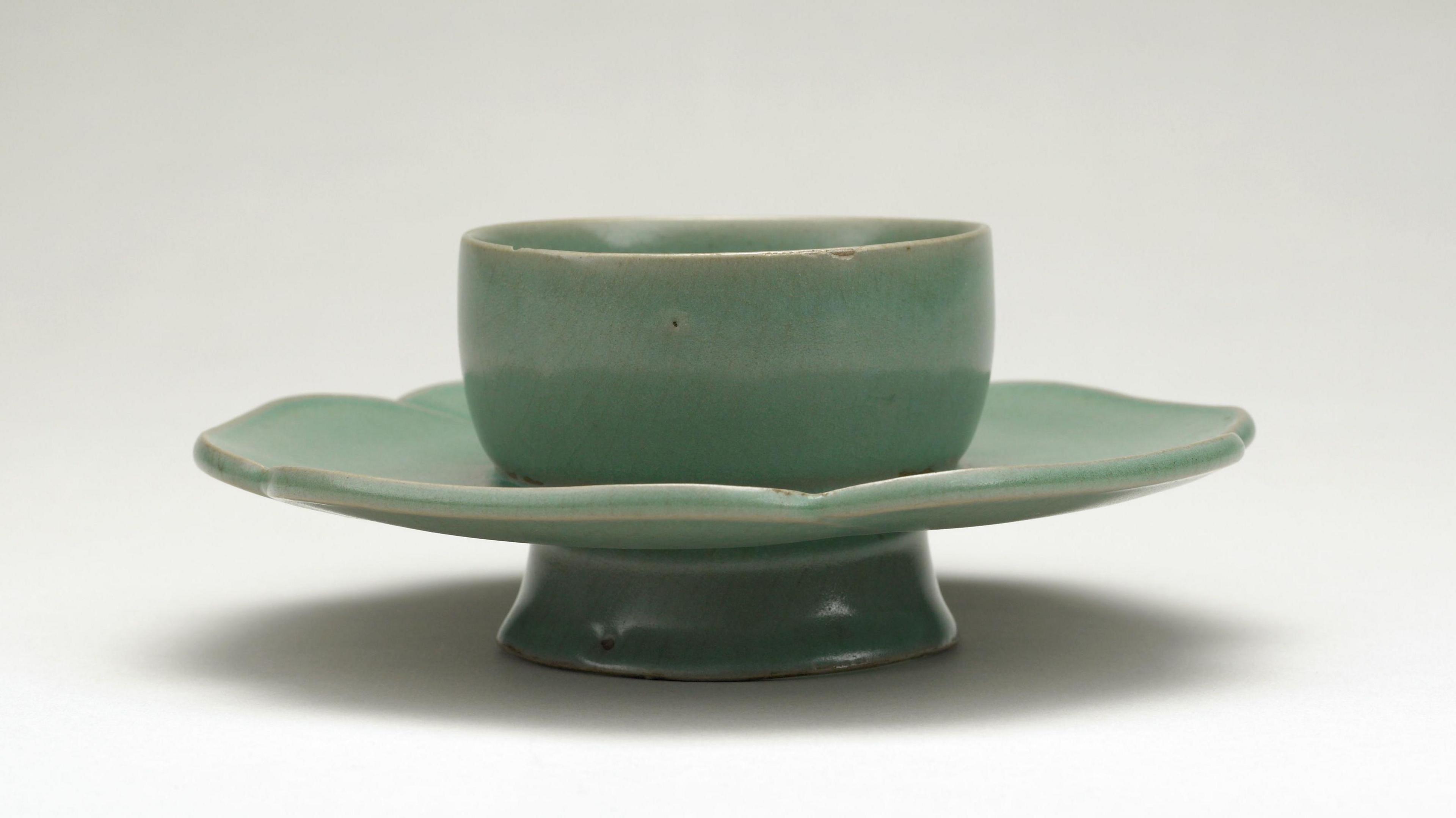 A green bowl stand which looks like a cup and saucer joined together