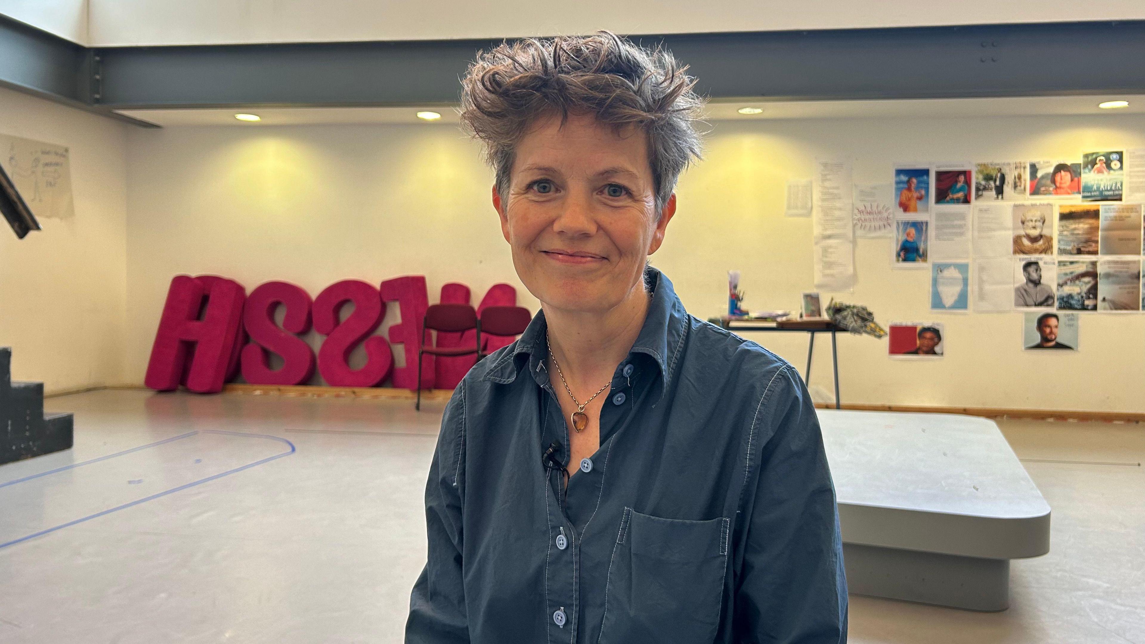 Sally Cookson, with short hair and wearing a blue shirt, in a rehearsal studio