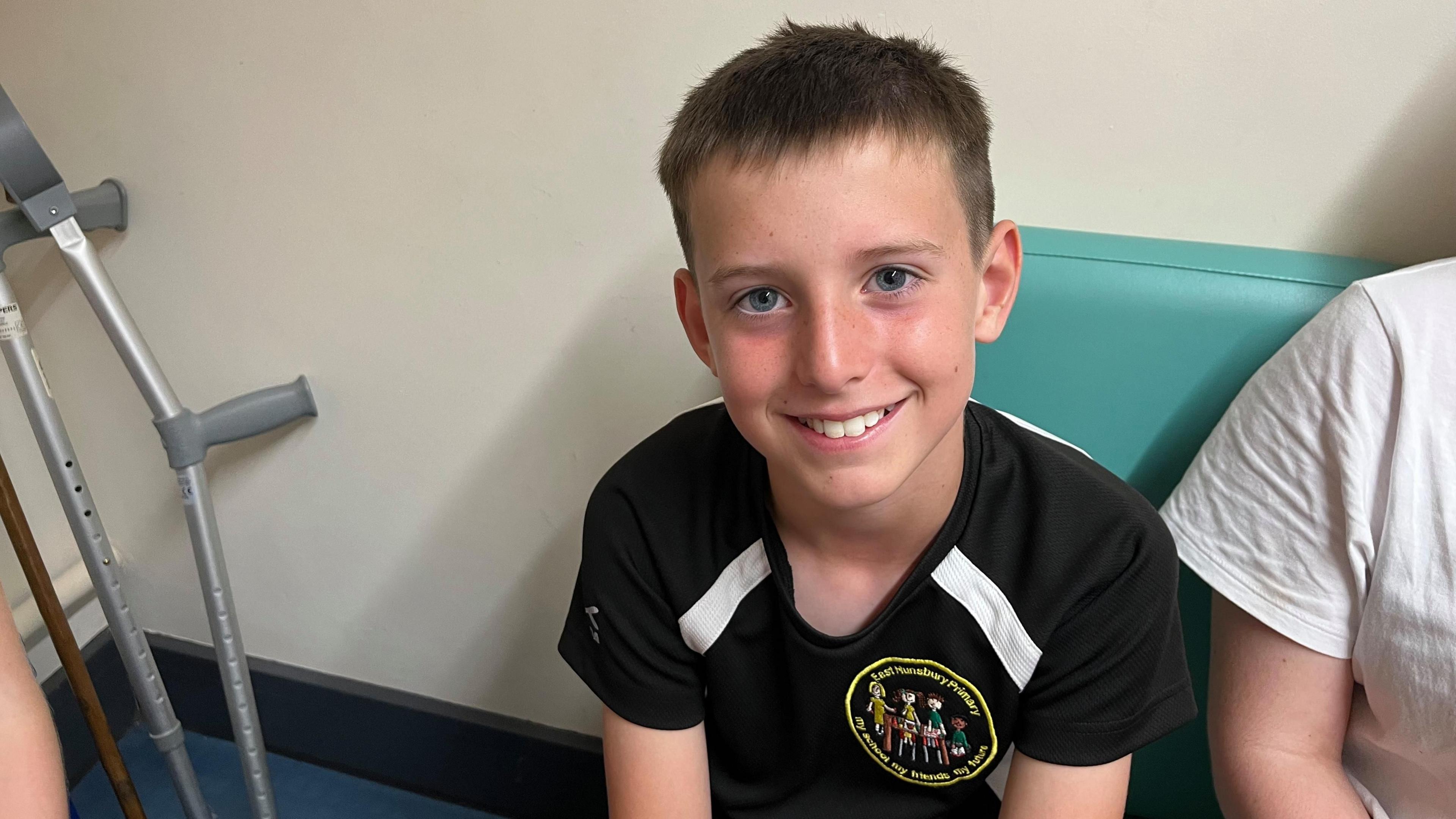 Boy with short brown hair in a black T-shirt smiling
