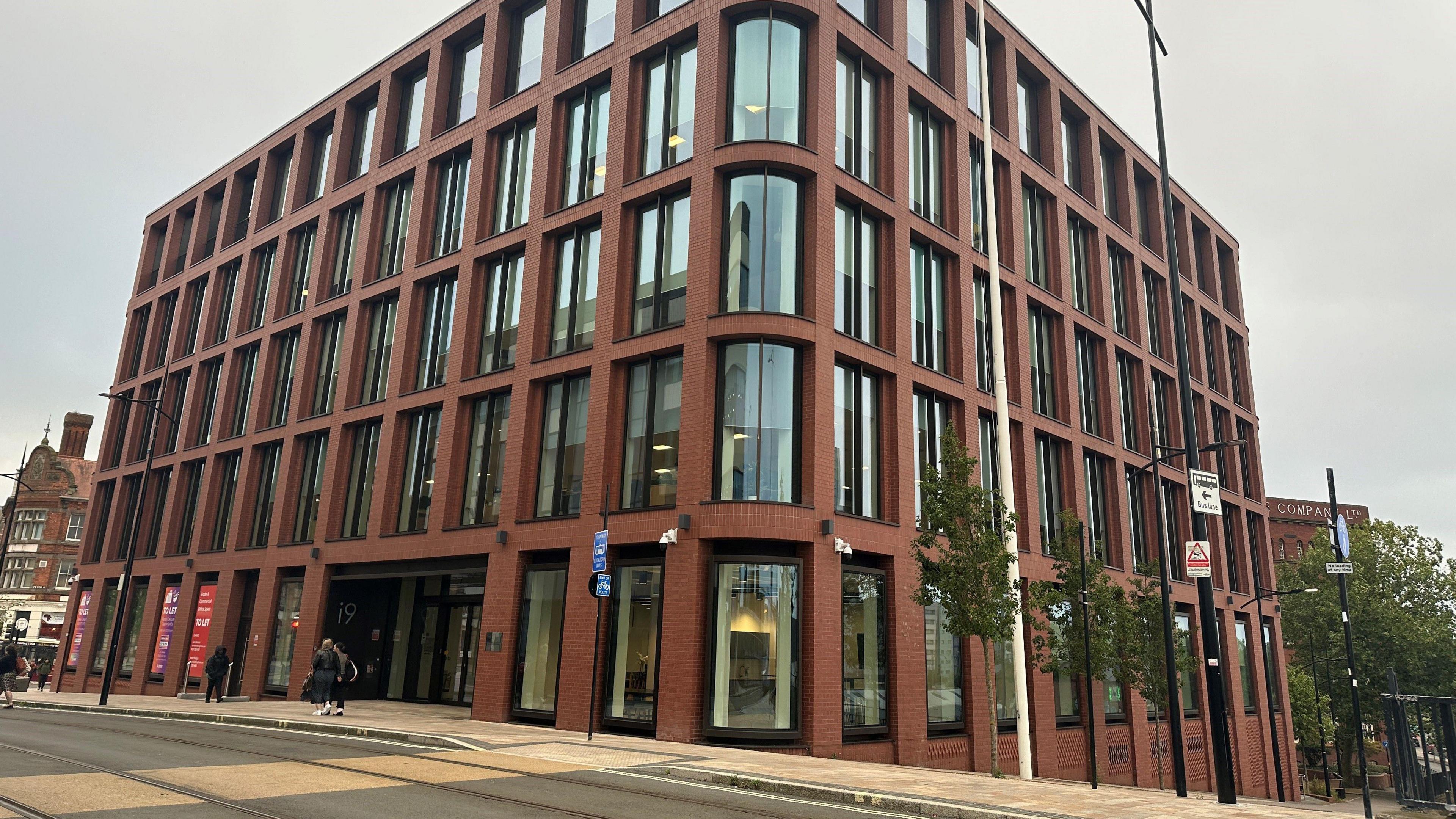 Photograph of a the headquarter, a red brick building with large windows. 