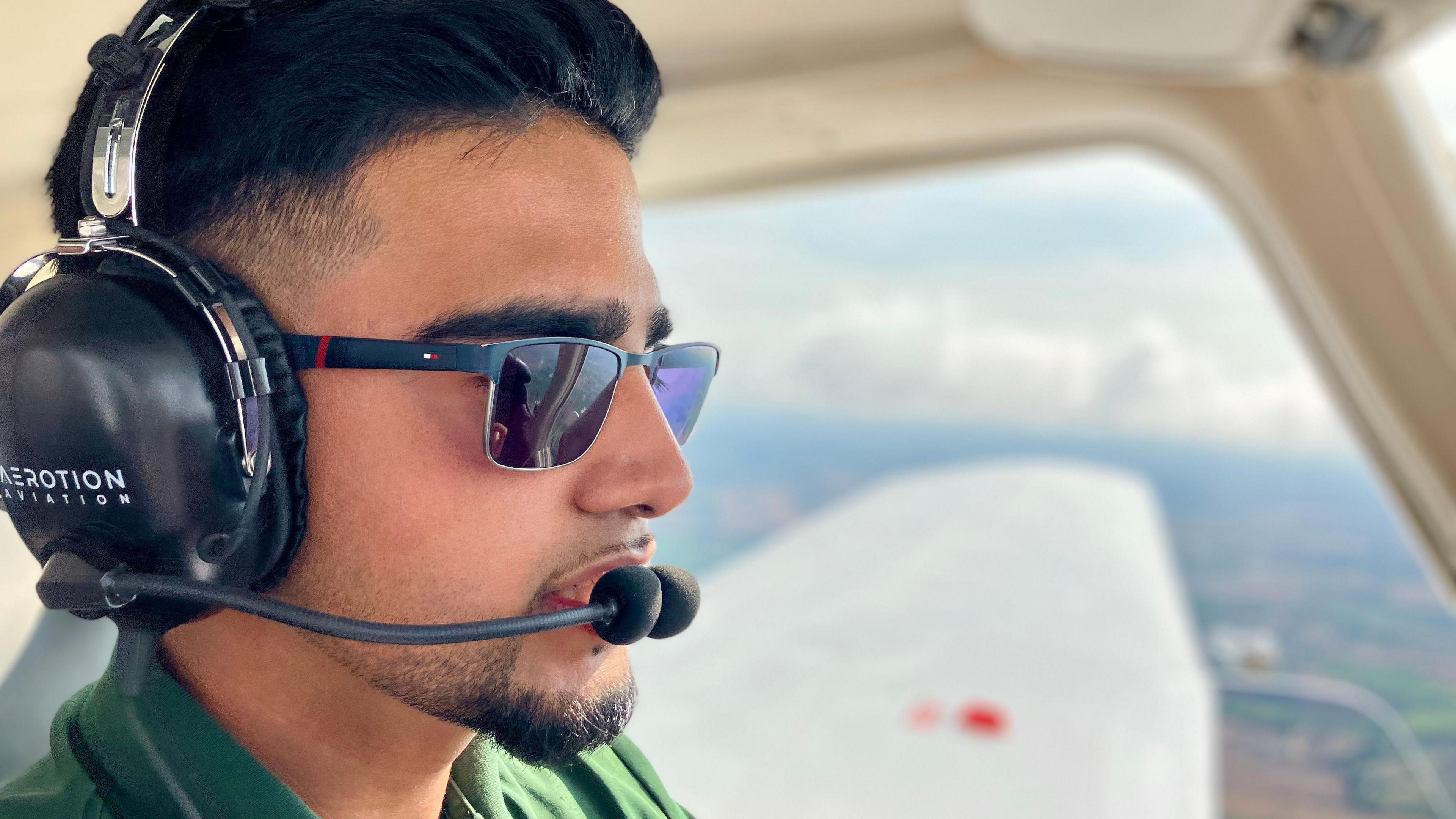 Close up of a teenage boy wearing a headset and flying a plane.