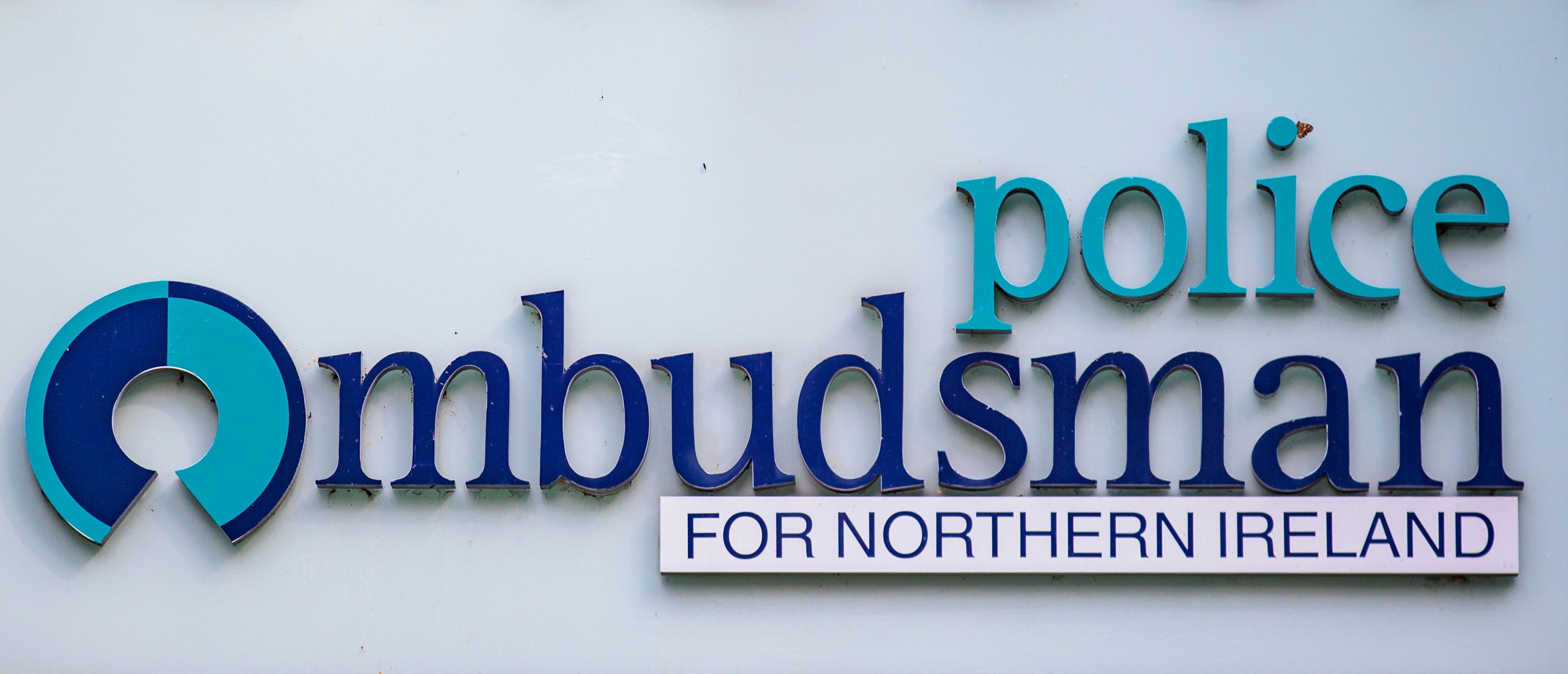 A sign with police ombudsman written in blue against a whitewall