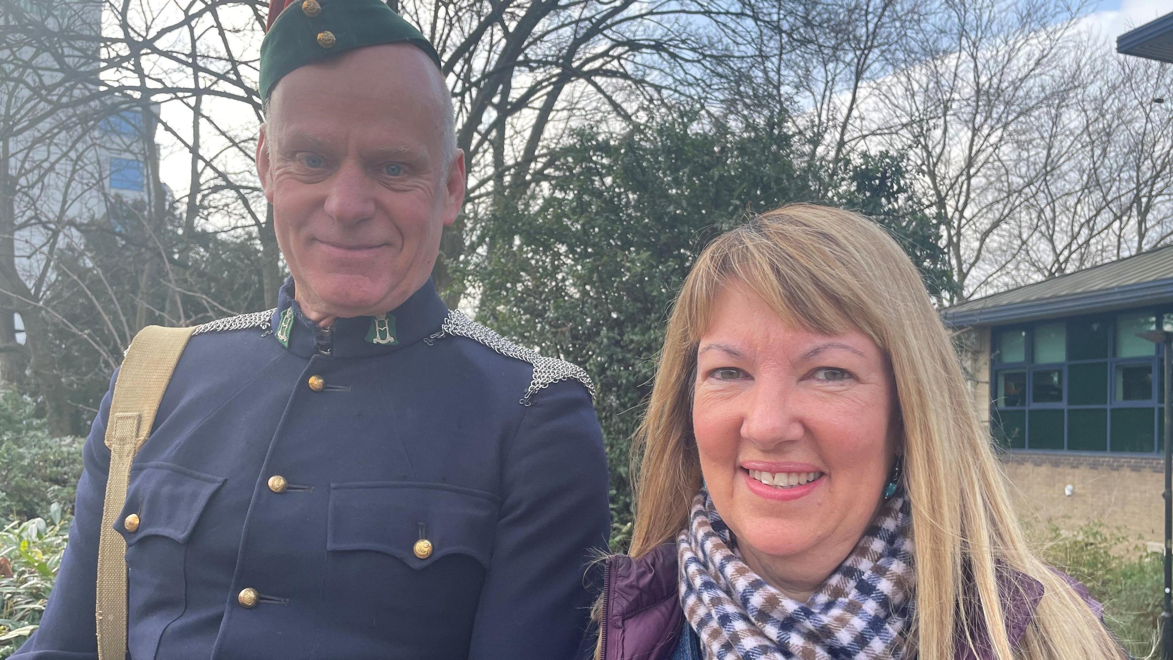 Neil Reynolds is wearing his fathers old military uniform, and is stood next to Cheryl Mays - who has long blonde hair.