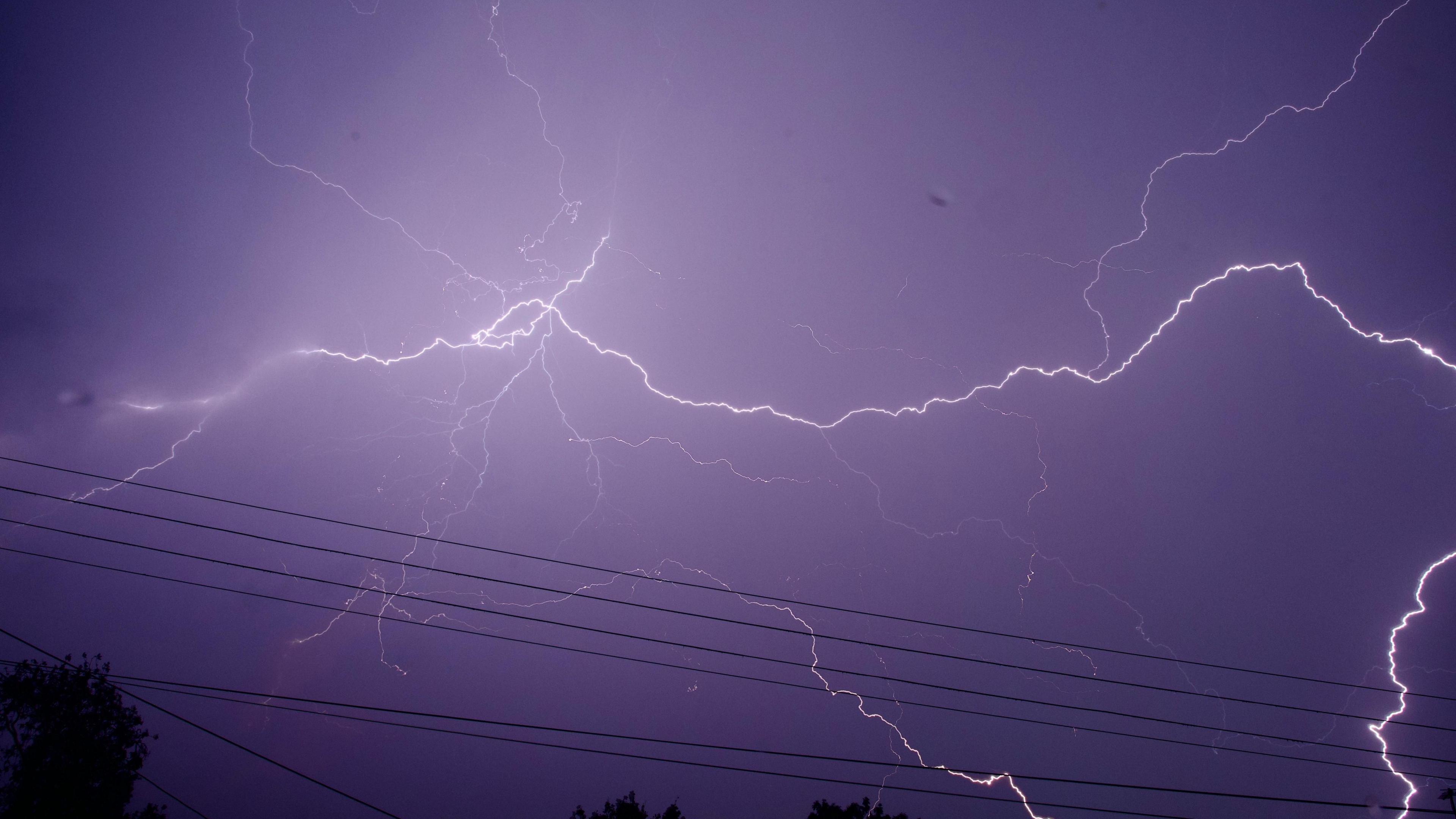 night sky turning a purple hue as fork lighting spreads across the sky.