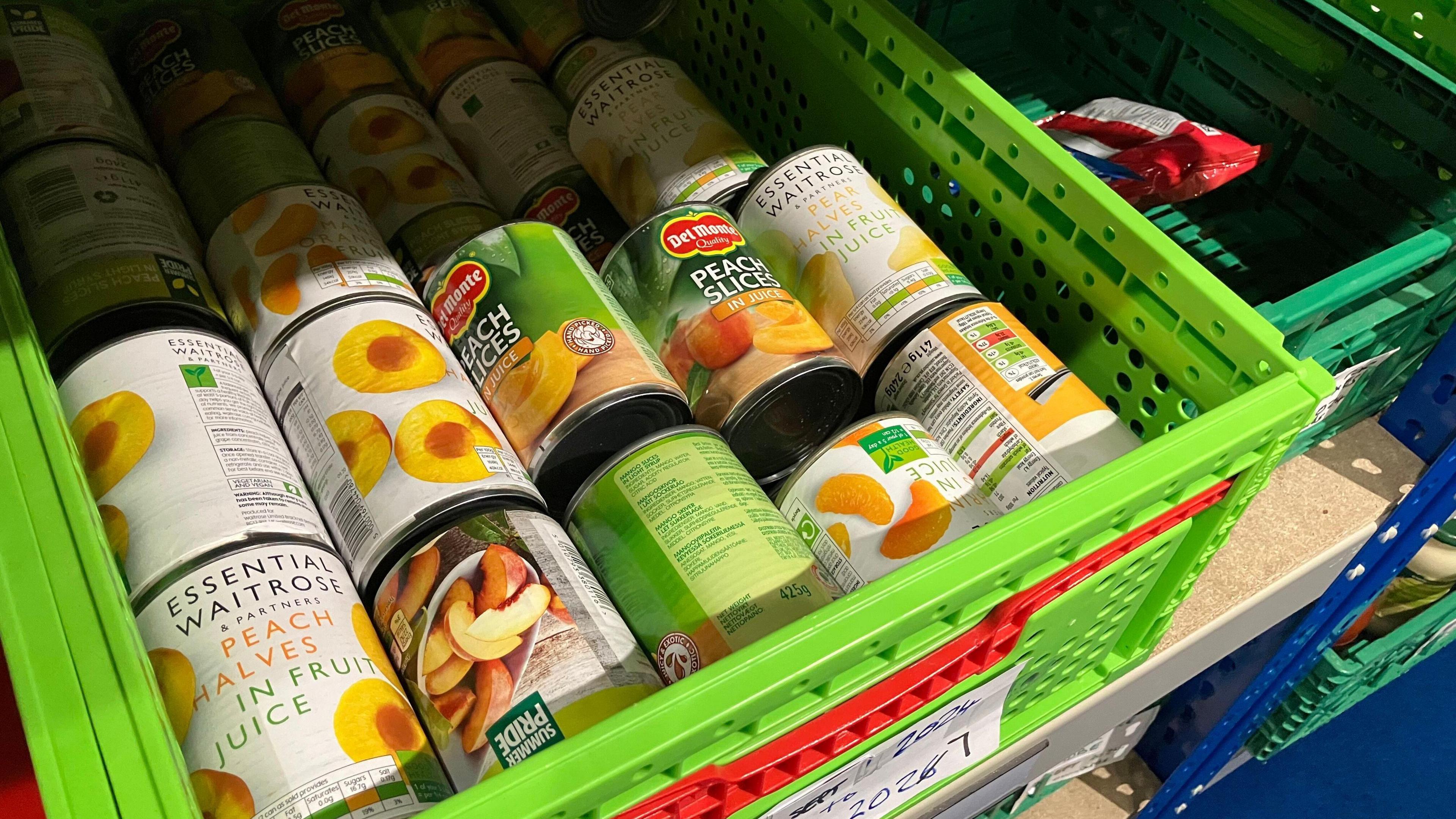 Tins of peach slices in a green tray