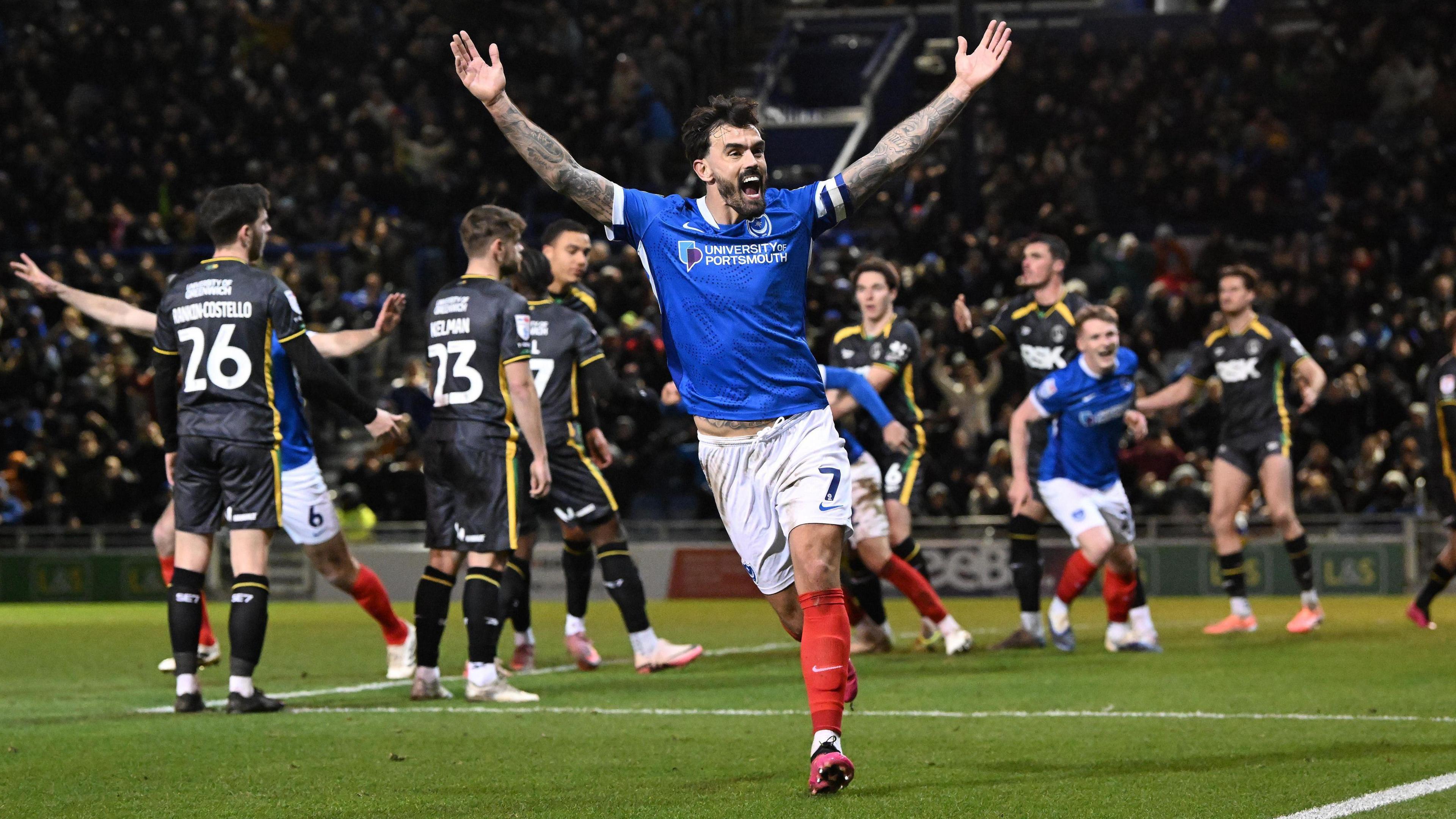 Marlon Pack celebrates in front of Portsmouth fans with arms out wide