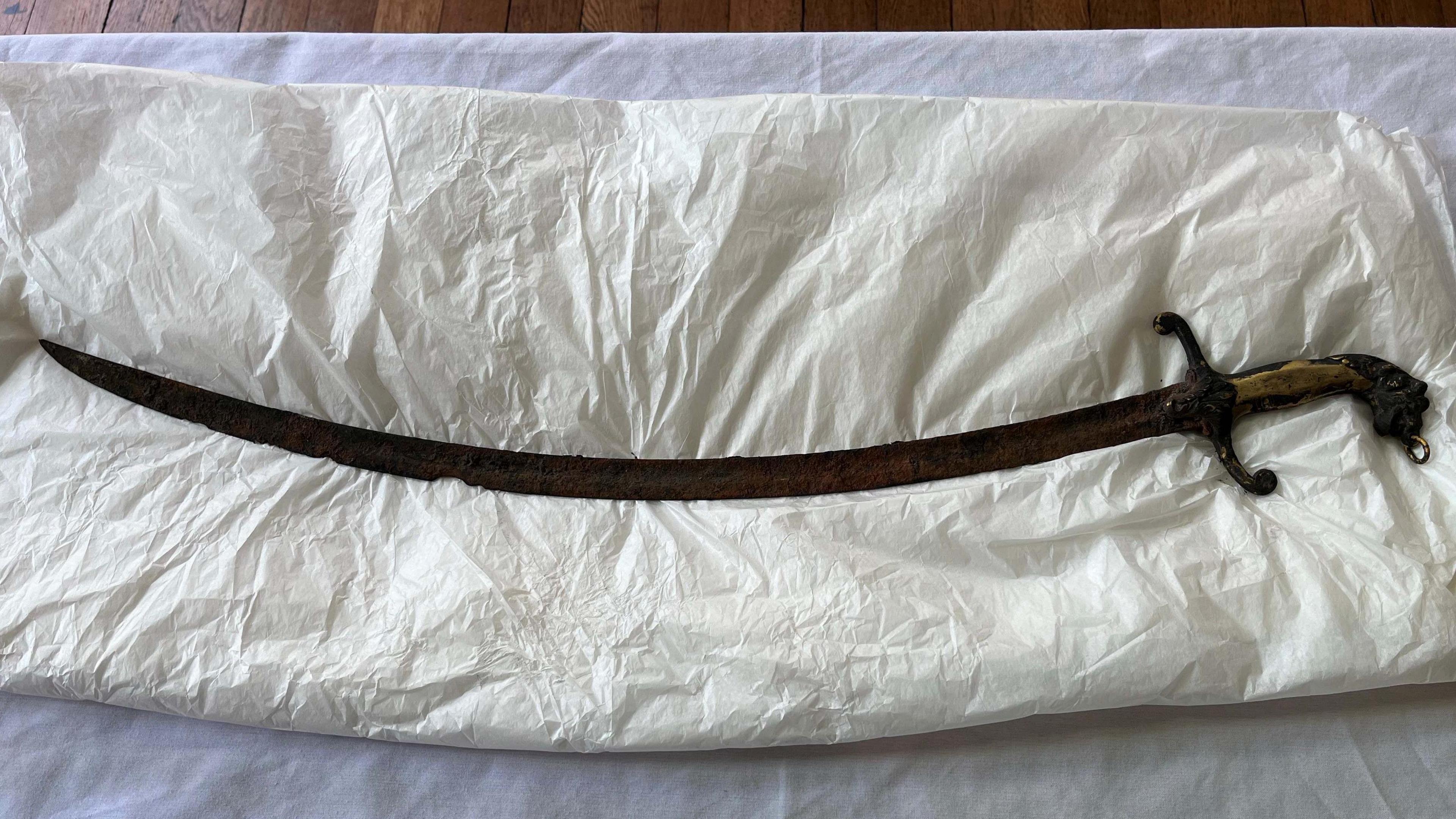 A long sword with a curved blade. It is rusty and chipped