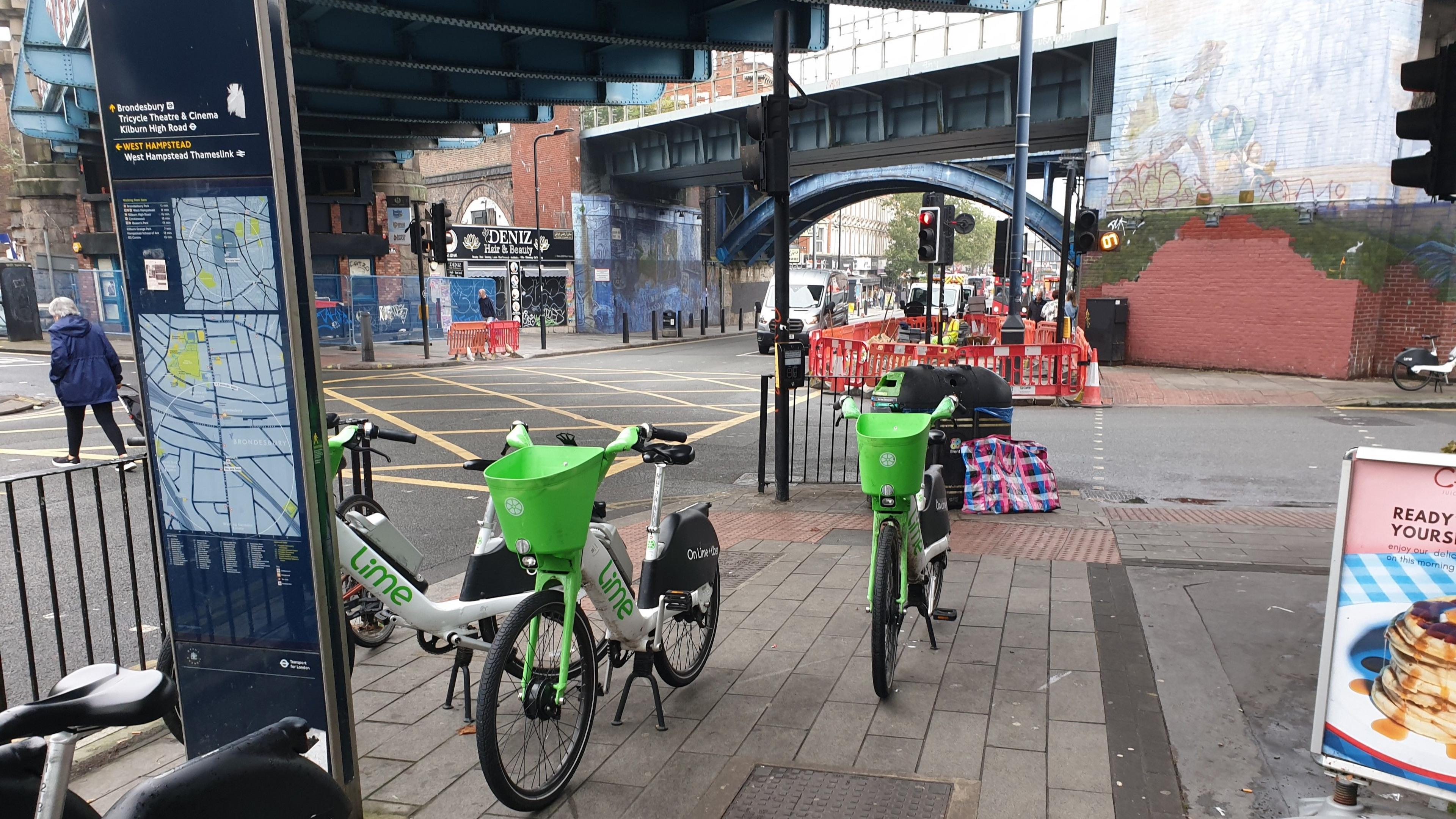 Three dockless e-bikes obstruct access to tactile paving at a road crossing in Kilburn which is used by visually impaired people to safely cross streets