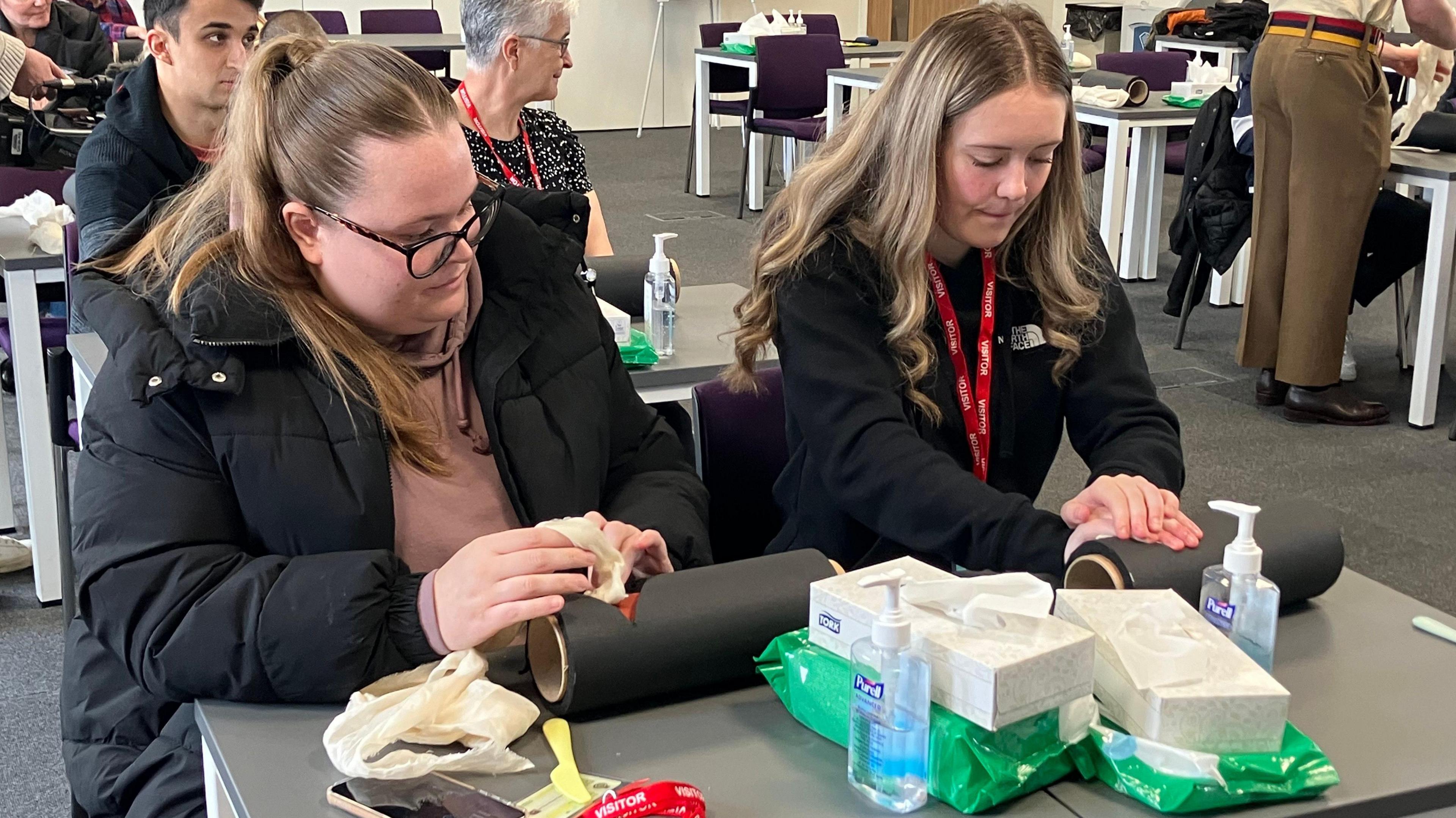 Two girls learning how to stop bleeding with equipment