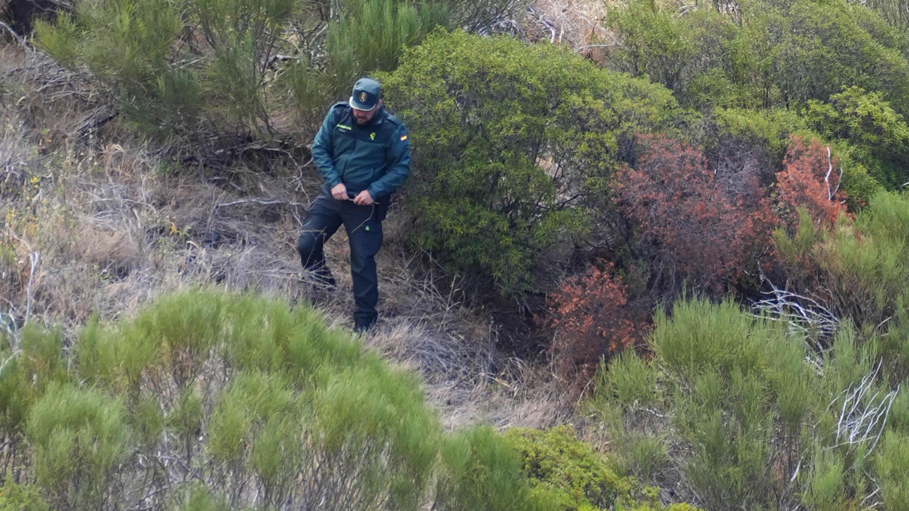 A Guardia Civil officer in green uniform descends down a ravine