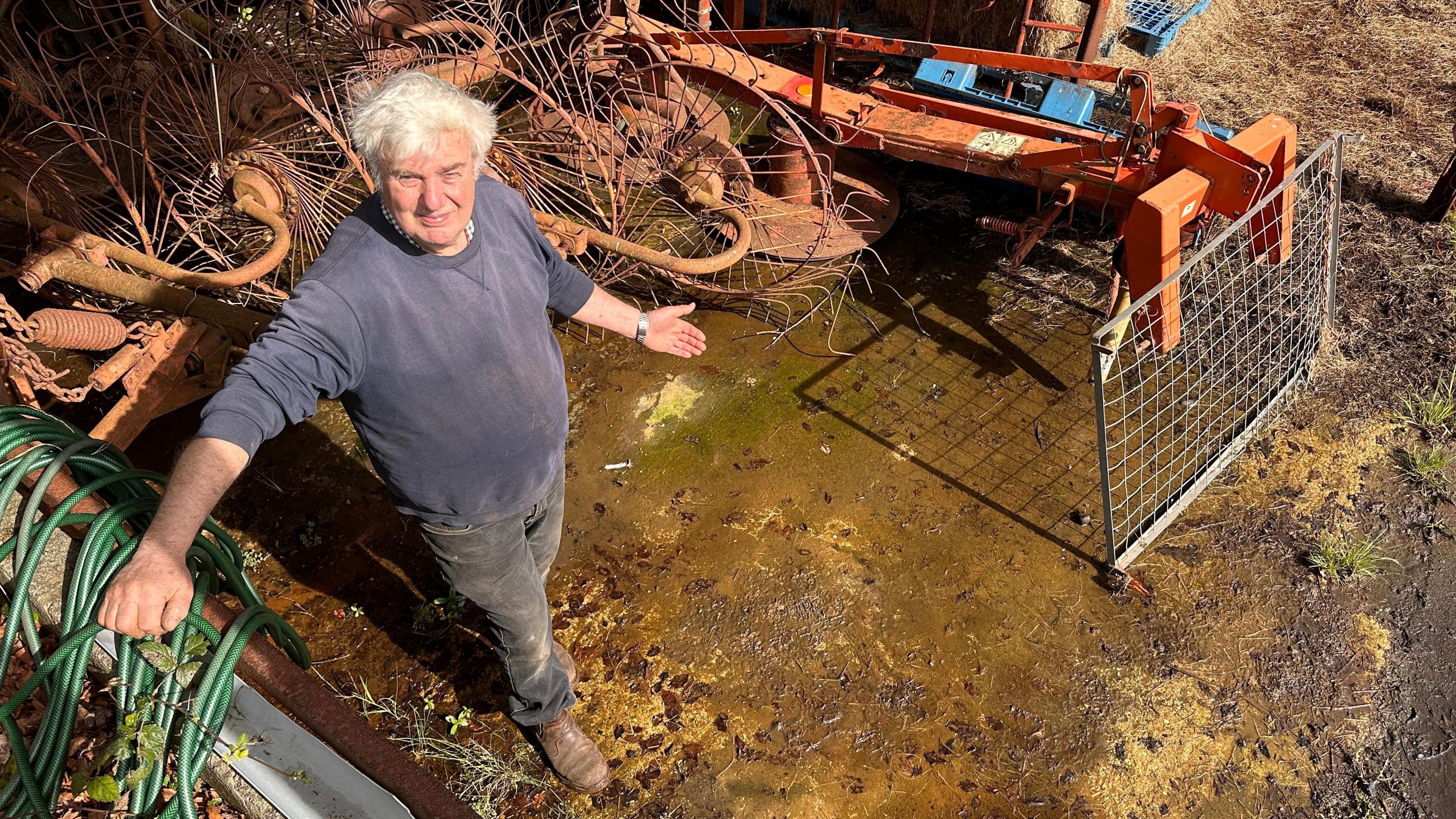 Farmer John Penny standing in a damp barn