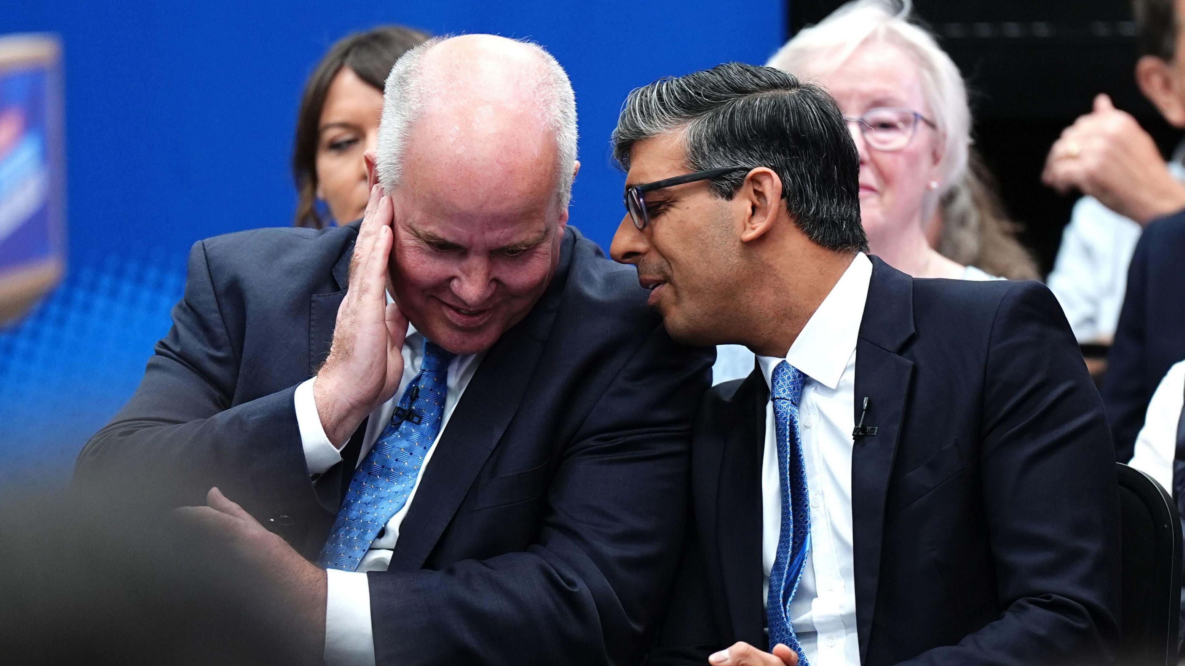 Rishi Sunak whispers into Andrew RT Davies ear as they sit beside eachother