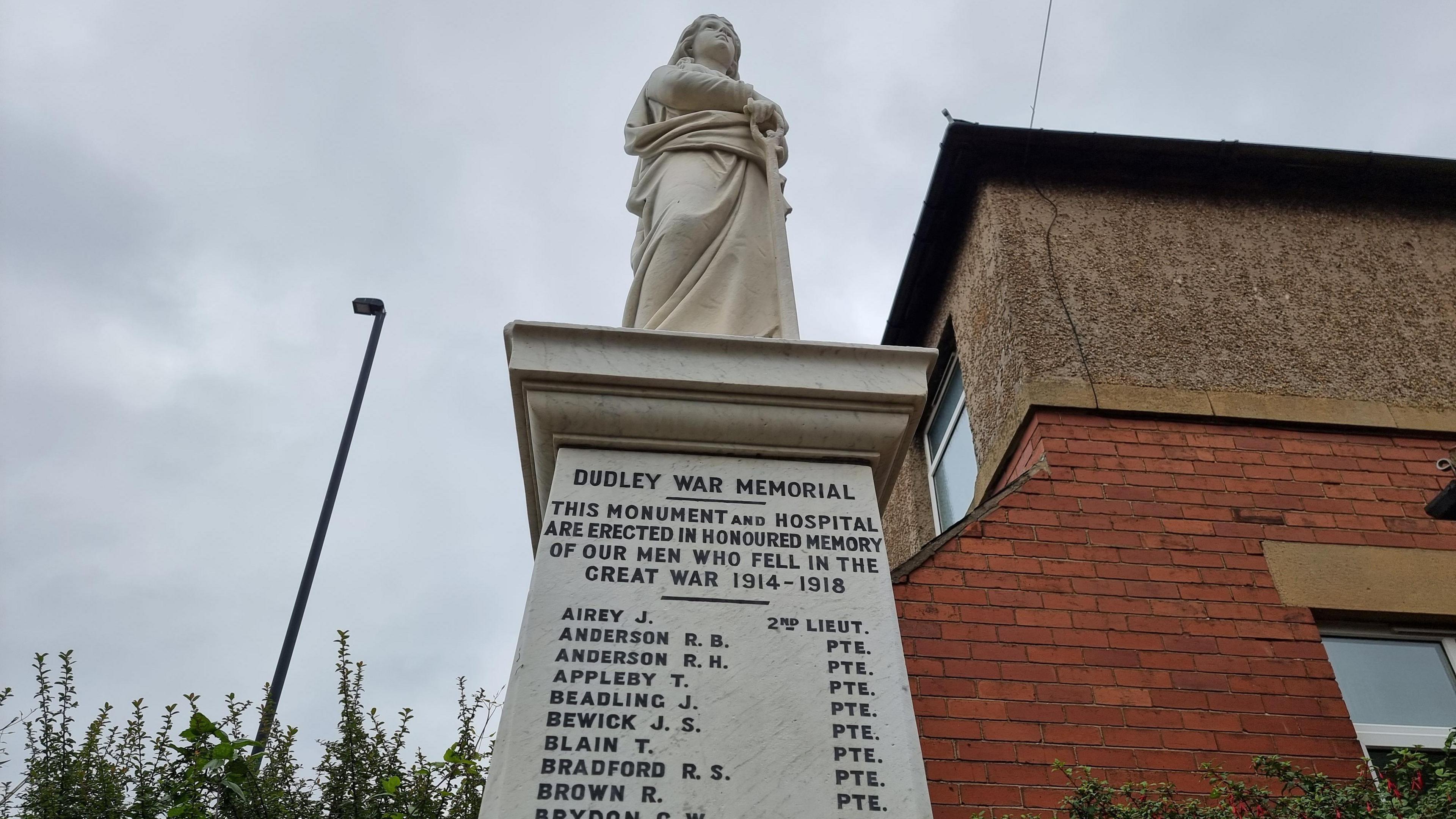 The Dudley war memorial is a white marble plinth with a statue of woman on top. A list of names is inscribed on the memorial, under another inscription which reads: "Dudley War Memorial".