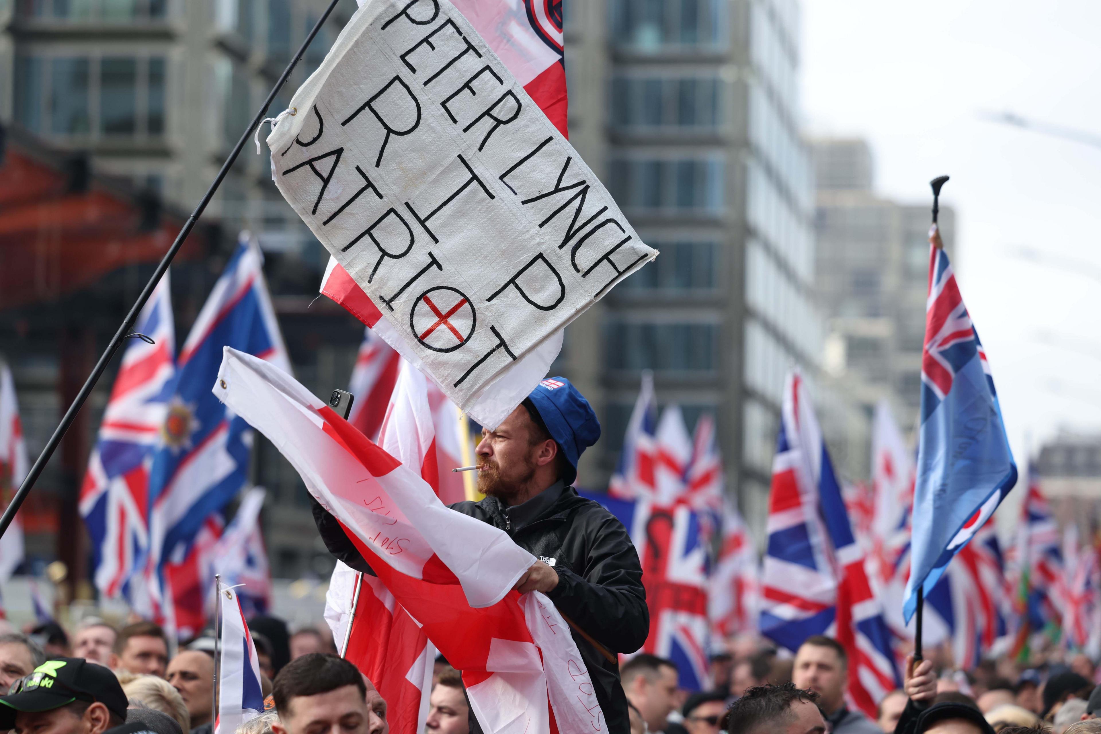 Marchers holding flags and a banner saying "Peter Lynch RIP patriot"