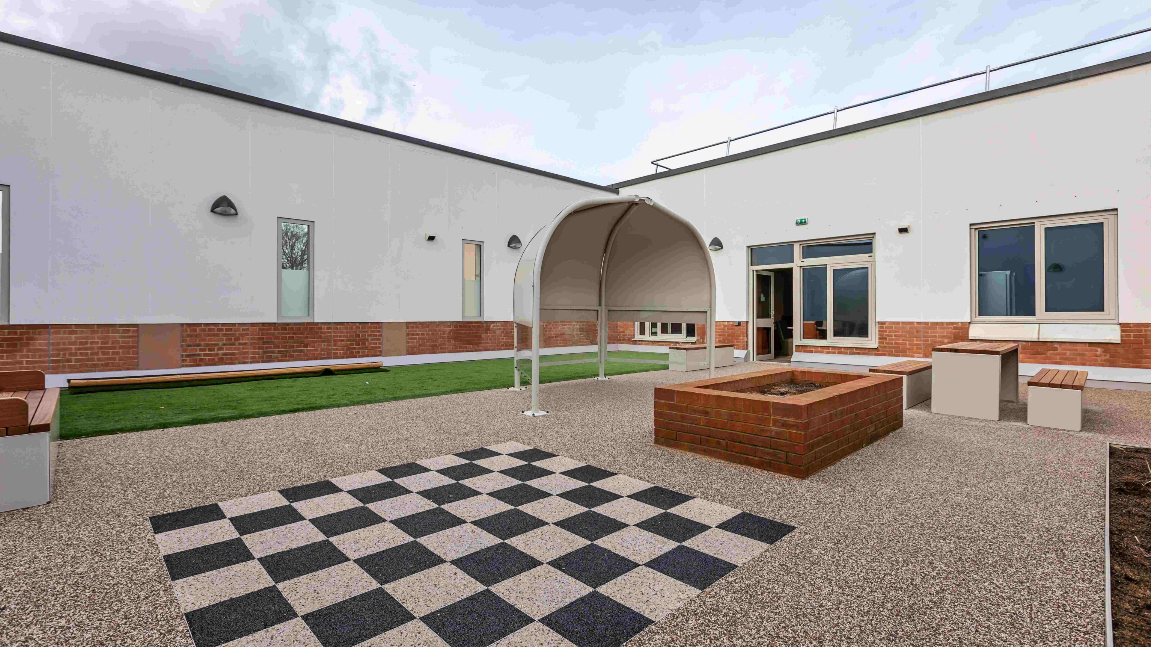 A courtyard area with checkerboards on the floor as well as a small turf grass lawn and seating areas.