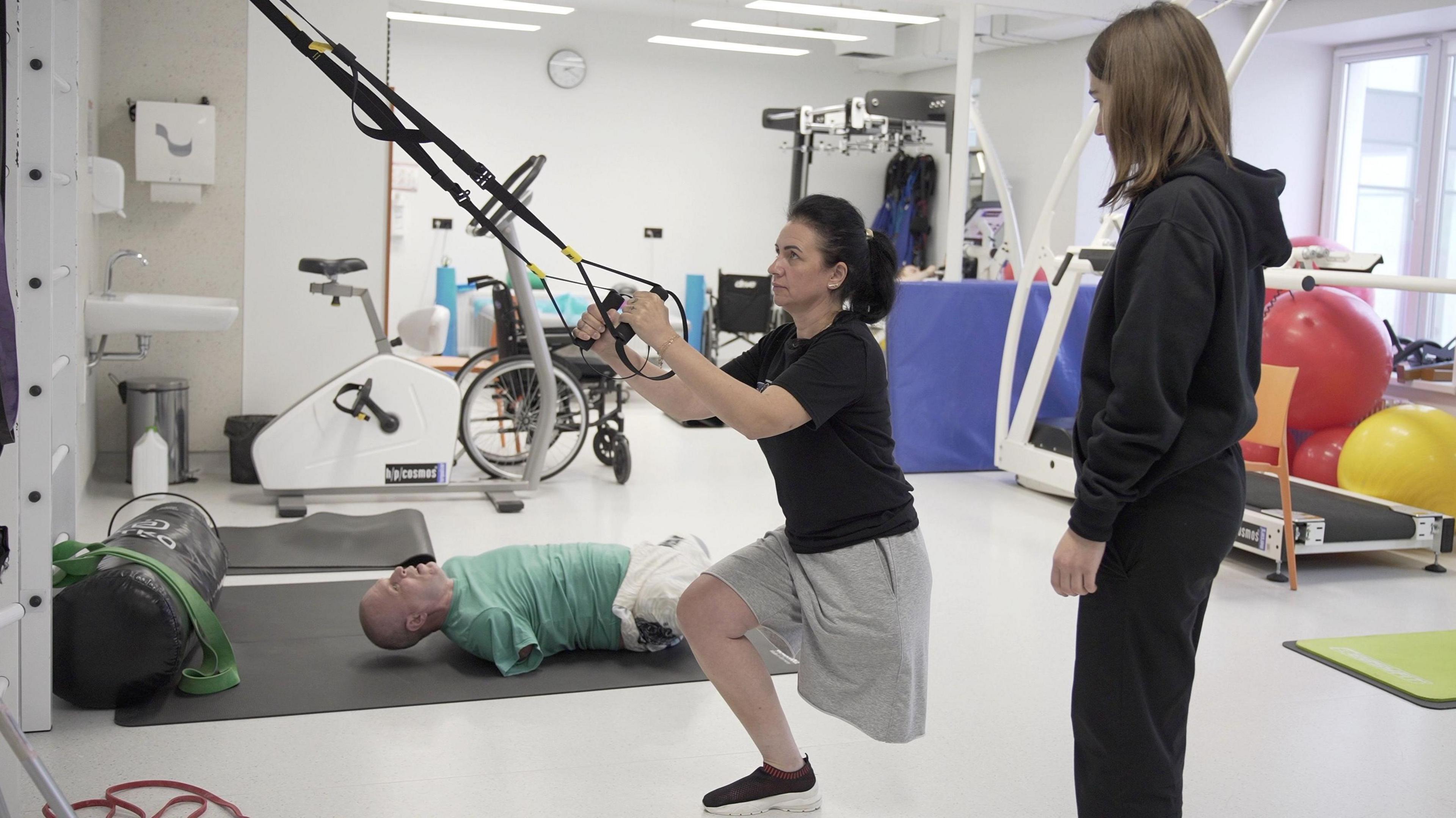 Olena, exercising her leg and upper body muscles with resistance bands