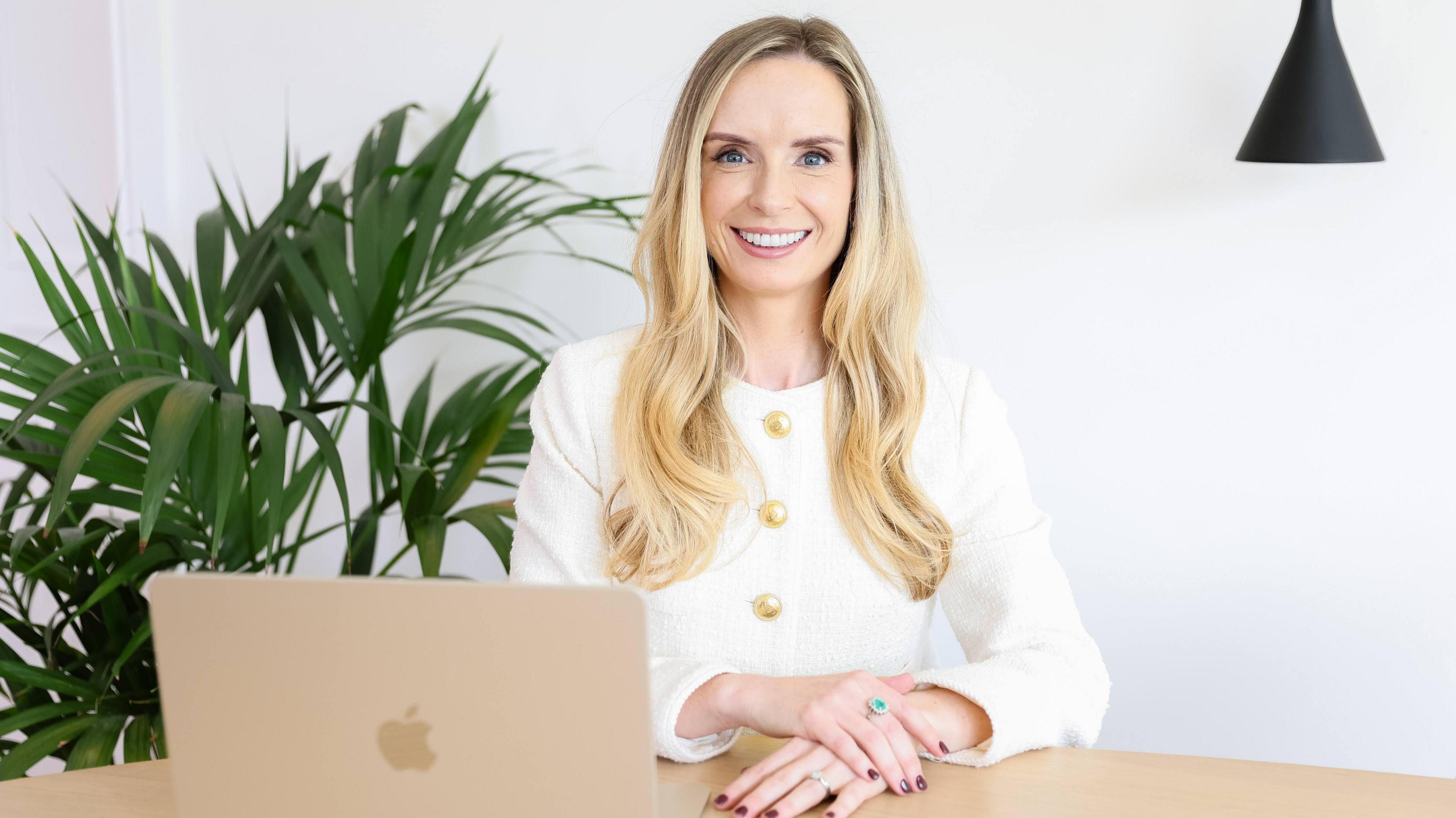 Medi Parry jones is sat at a desk with a laptop in front of her. She is smiling at the camera