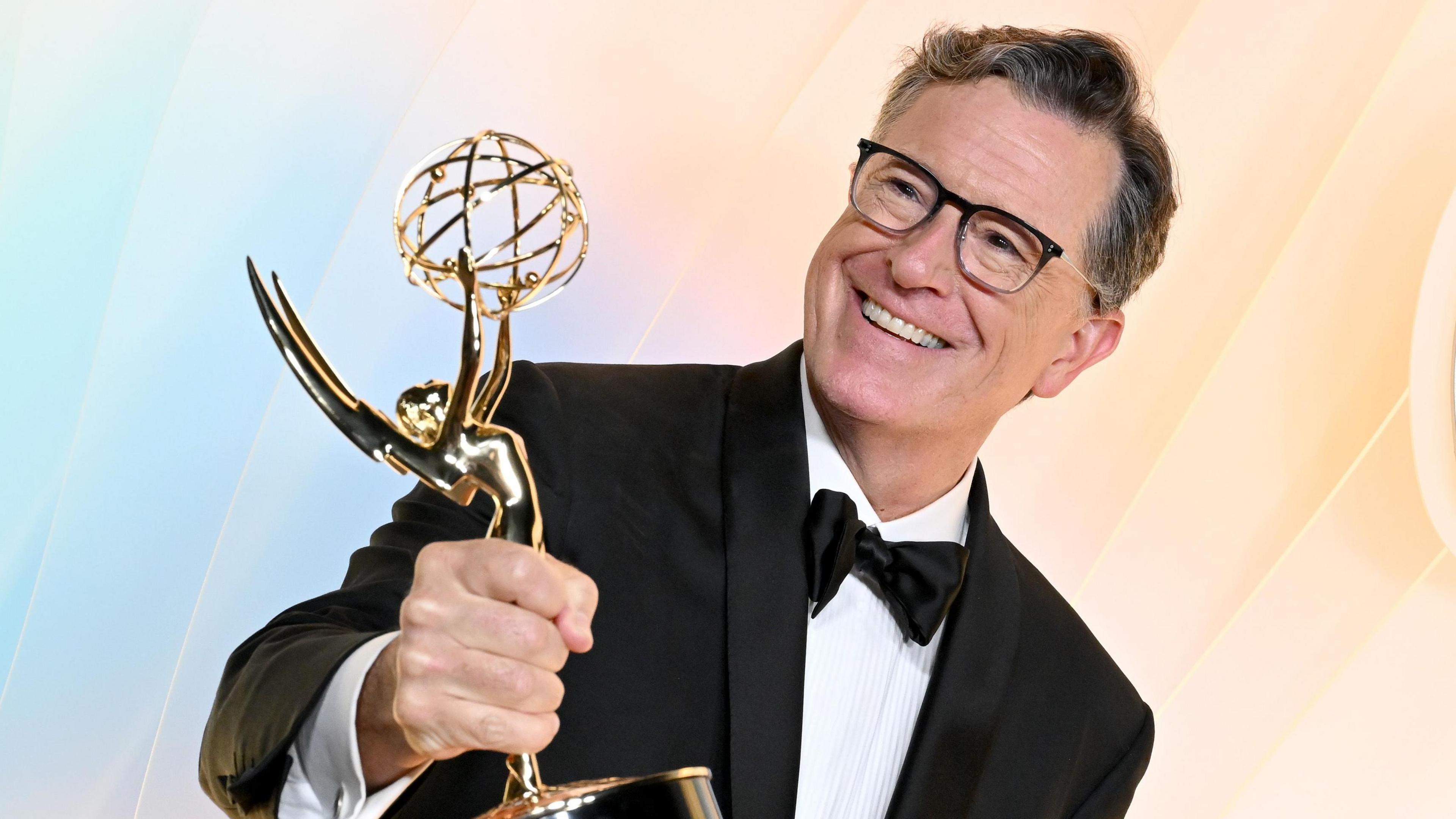 Stephen Colbert holding up his Emmy on his way in to an Emmys after party on Sunday