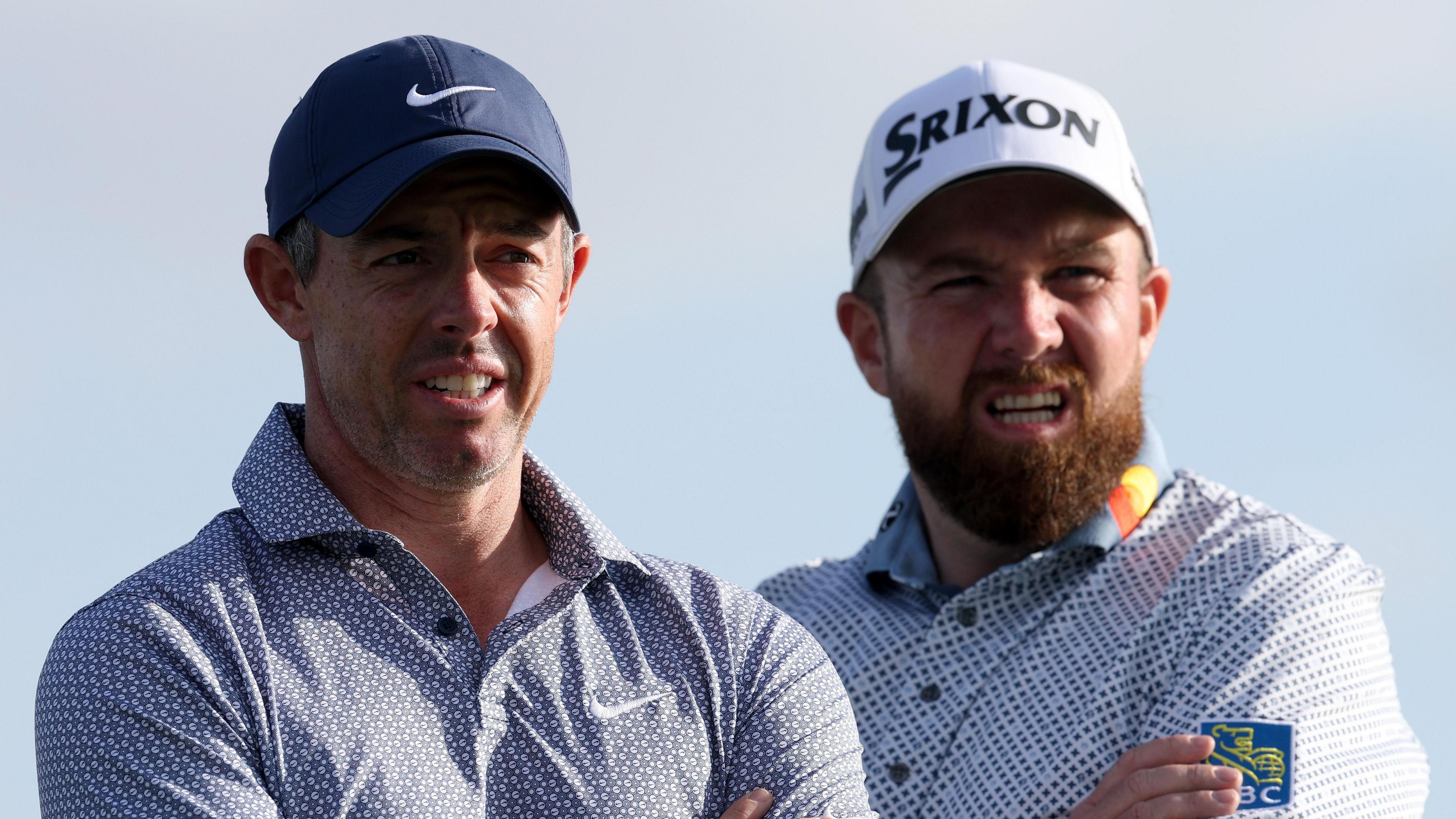 Shane Lowry and Rory McIlroy walking off a green during a windy round of golf in Dubai.