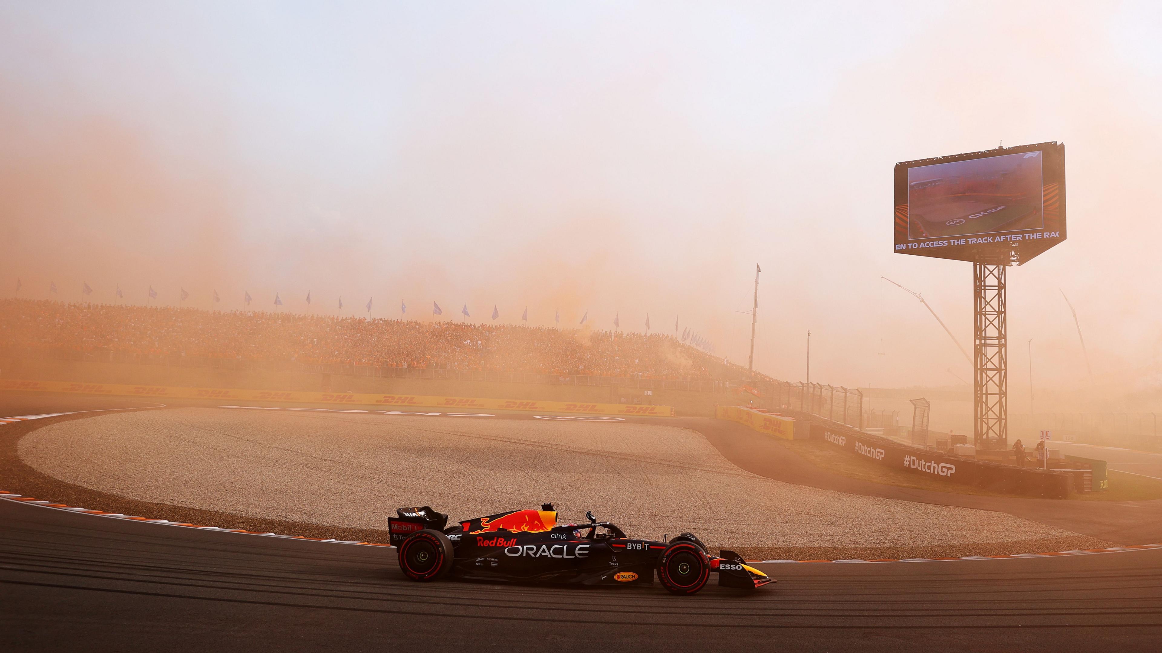 Red Bull's Max Verstappen drives around a hairpin with orange smoke in the air after Dutch fans let off flares during the 2022 grand prix