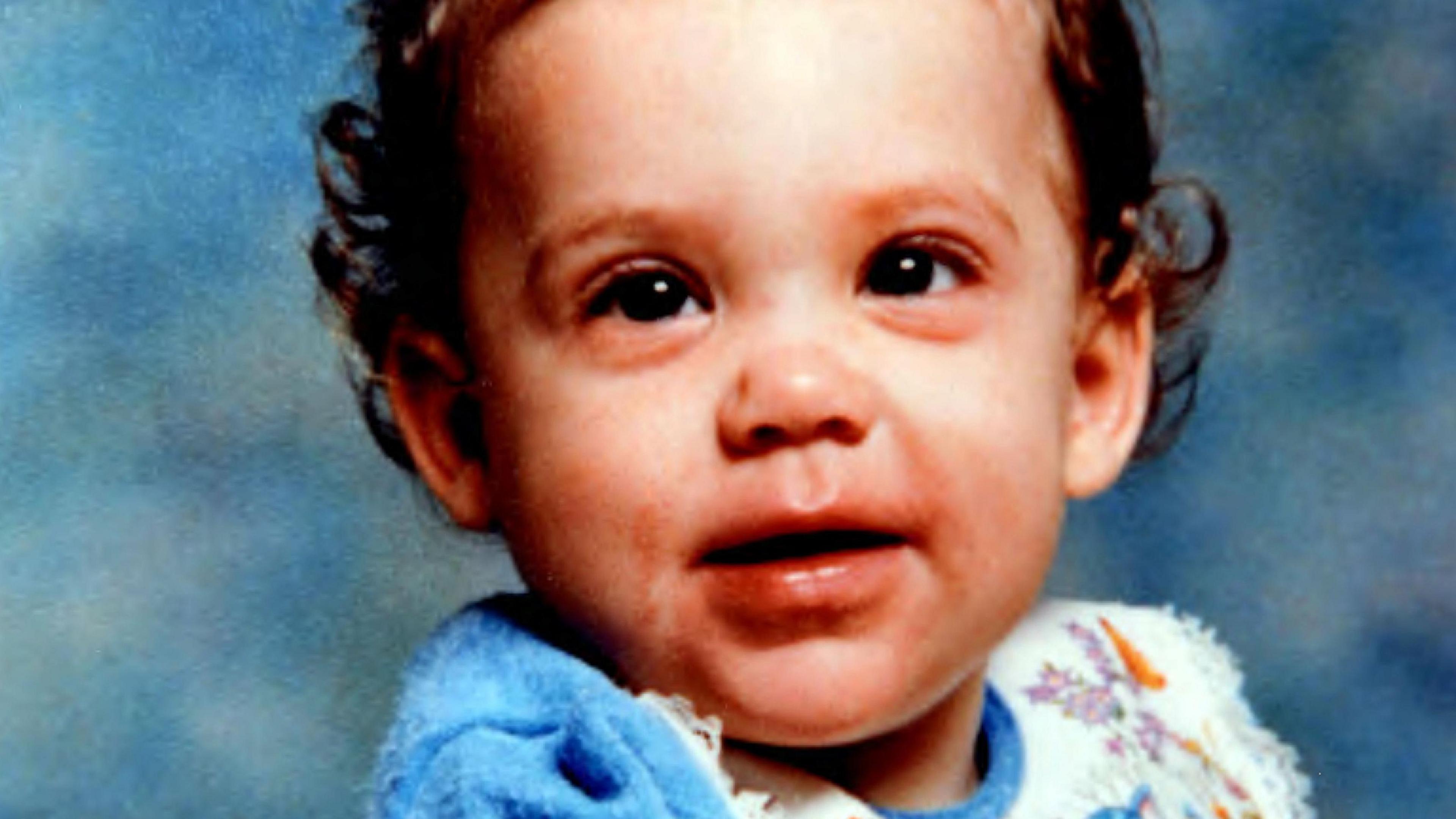 Picture of Katrice Lee. She has brown curly hair, brown eyes and is wearing a blue and white top in front of a blue background