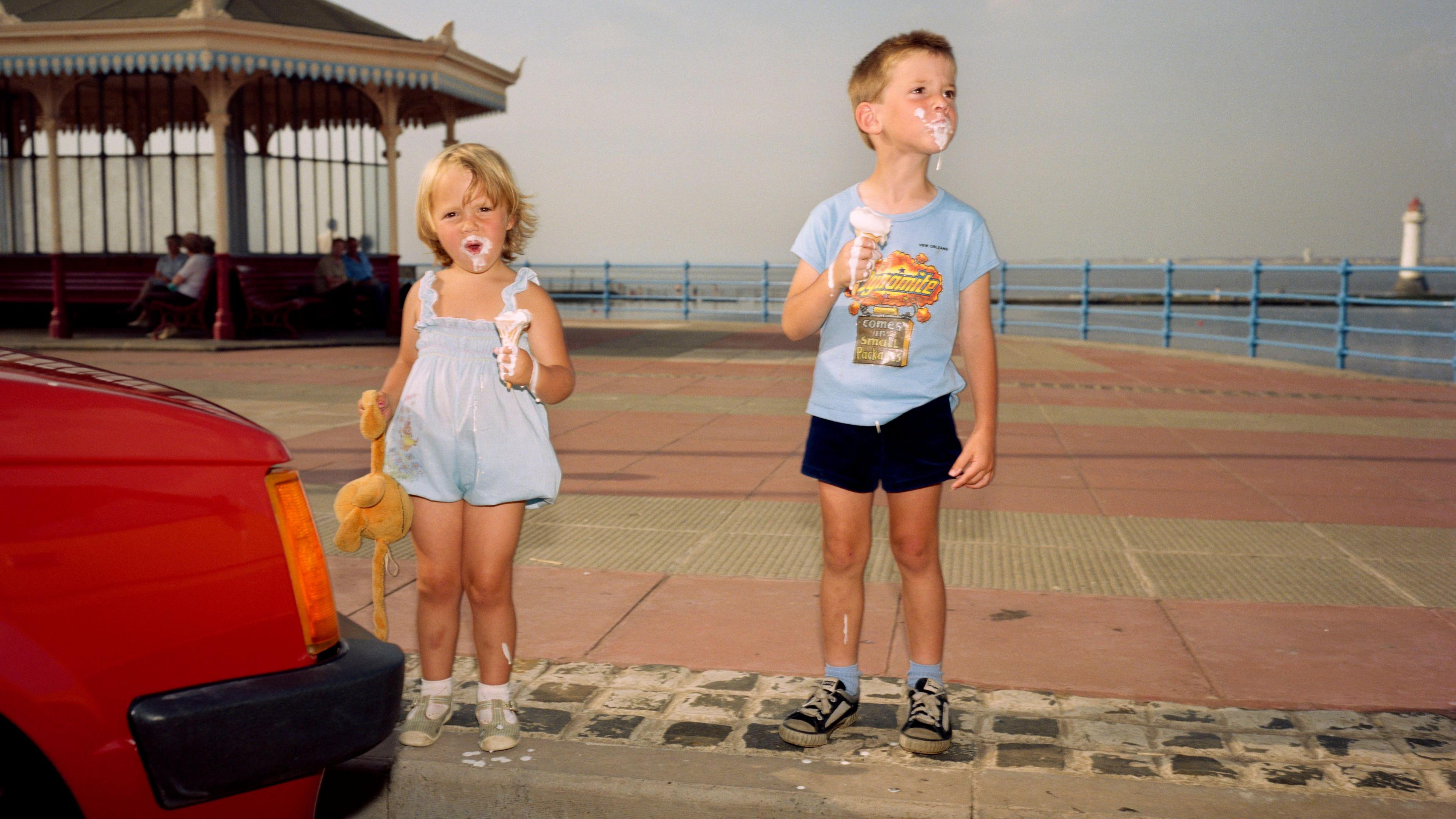 Two children enjoying an ice cream on a beach promenade 