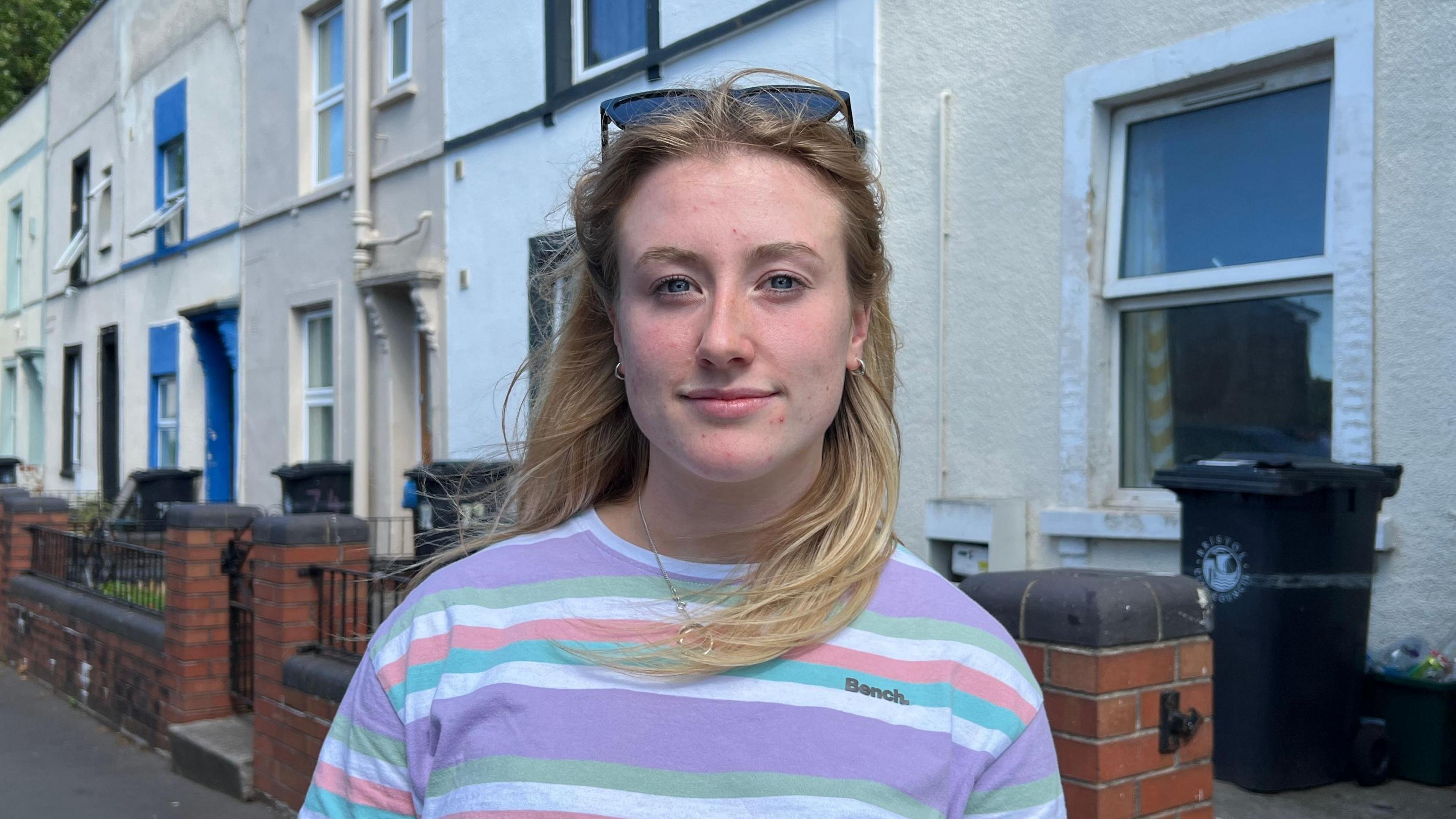 Becky Hopkins looking into the camera in front of a row of houses