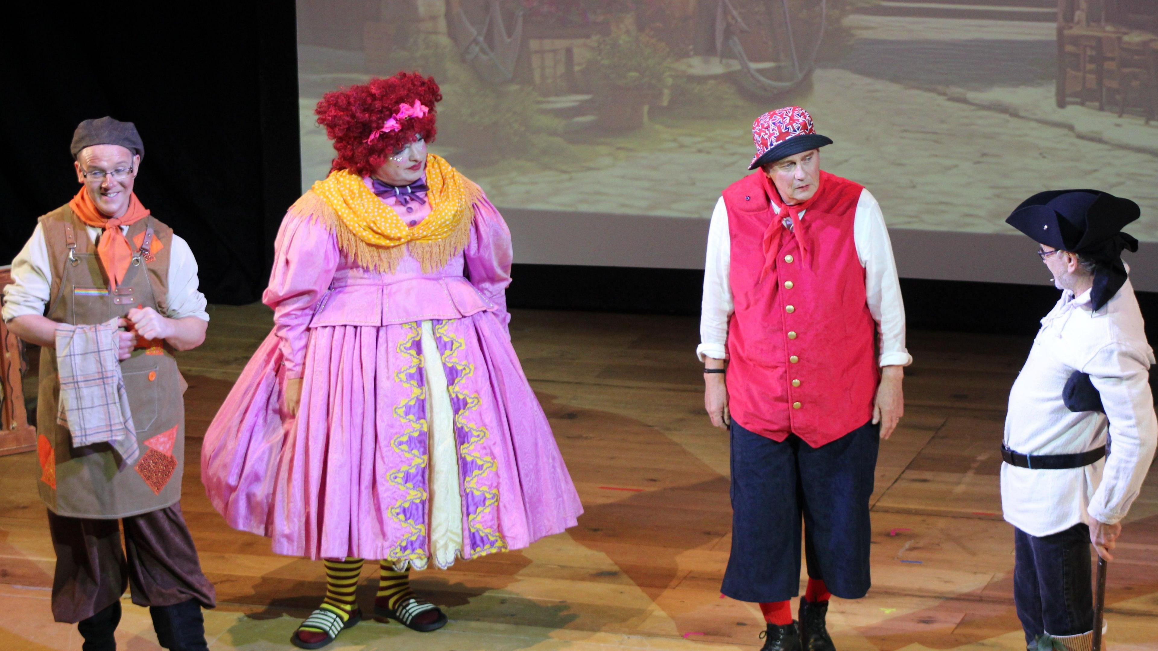 Four people in pantomime costumes on stage.