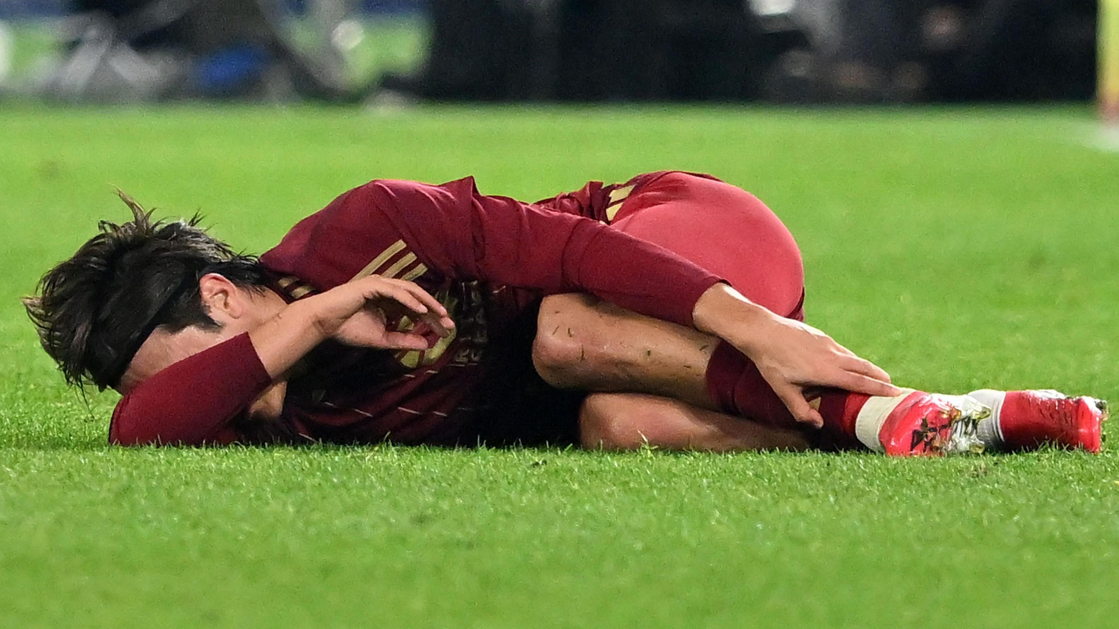 An unidentified player clutches his ankle and covers his face
