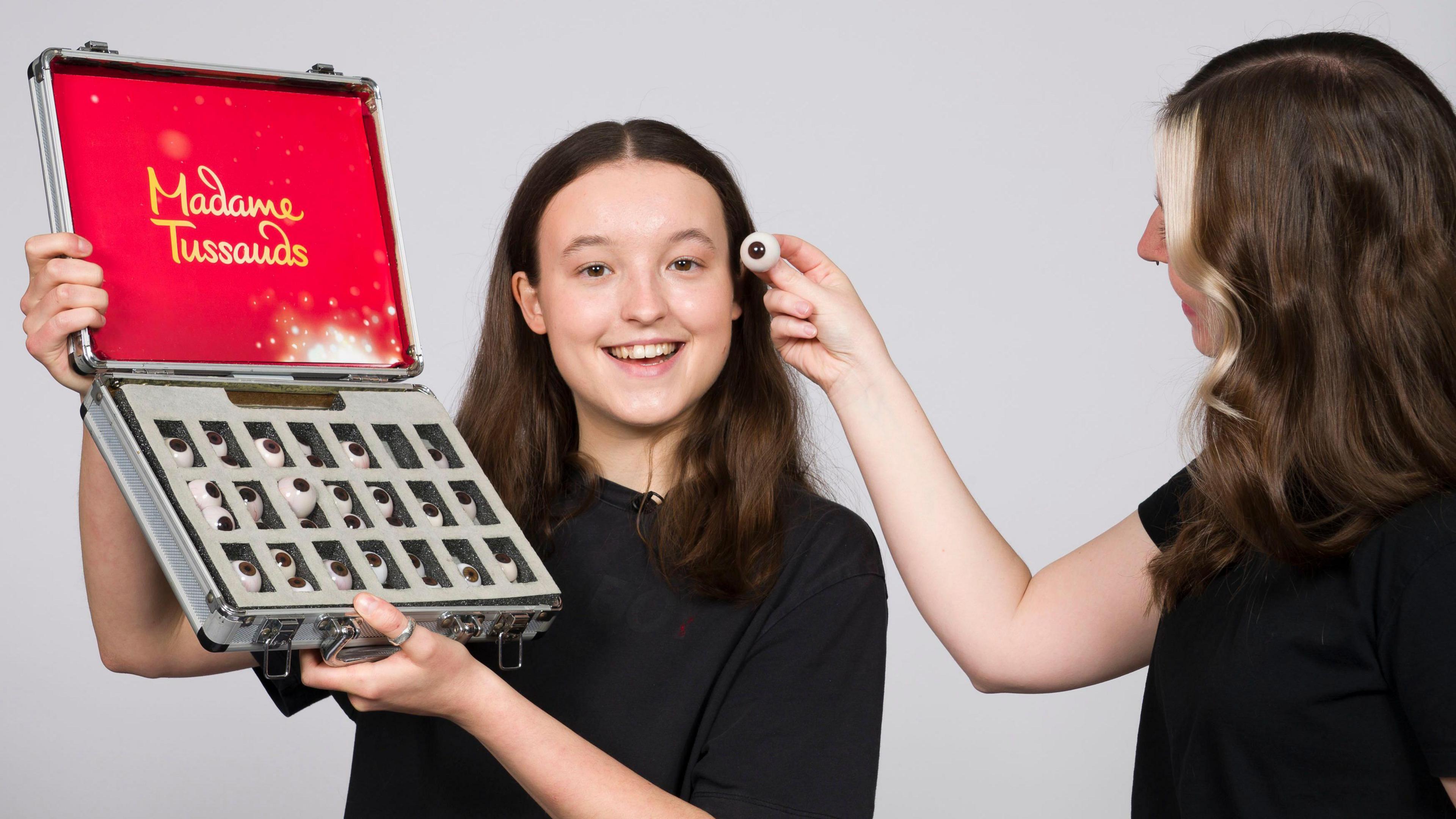 Bella Ramsey during the measuring up process for their first figure for Madame Tussauds London. A person is holding up a wax eye to compare with Ramsey's.