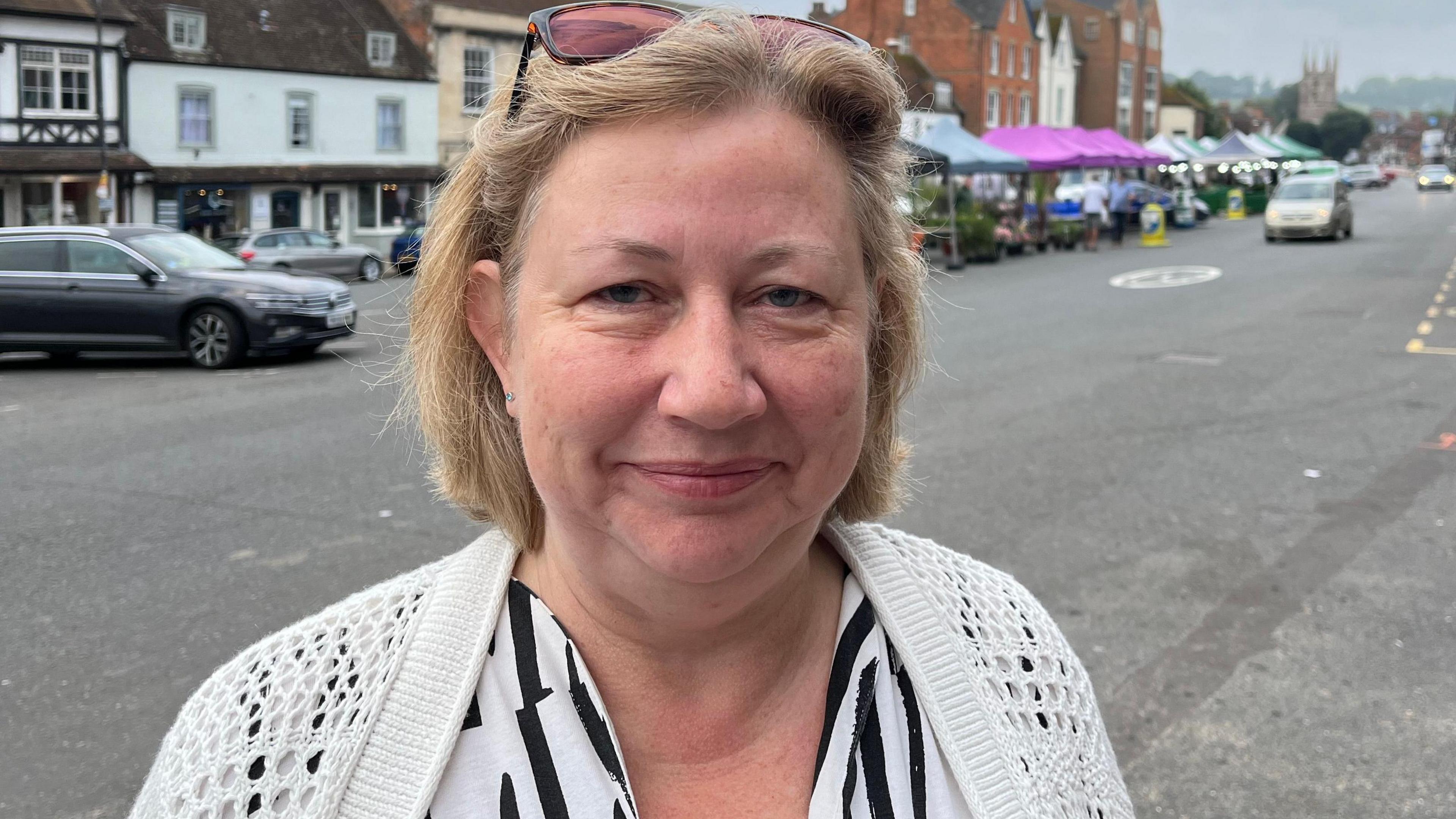 Marlborough mayor Kym Marie Cleasby stood at Marlborough Market.  Market stalls can be seen behind her and a church is in the distance.