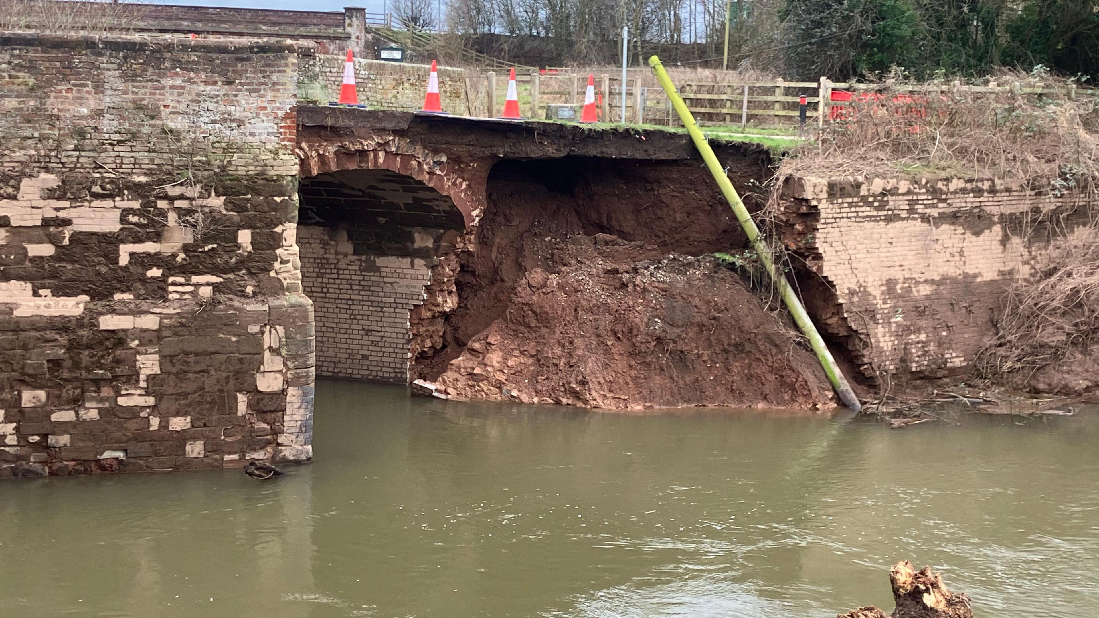 The remains of a 15th-century bridge structure, with part of the brickwork exposed.