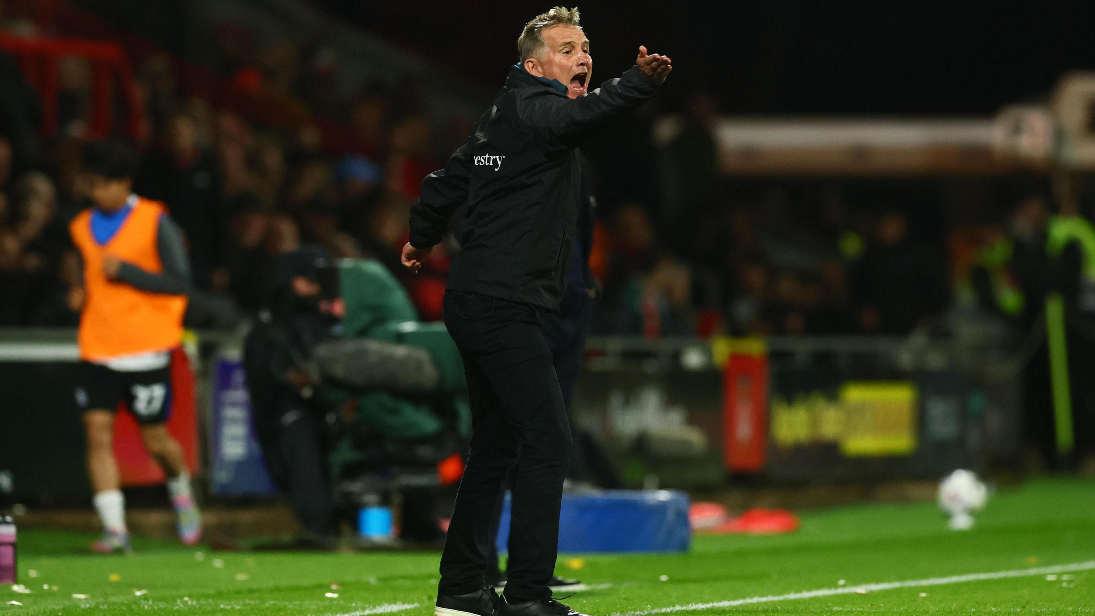 Phil Parkinson shouts with his arm outstretched during a Wrexham game 