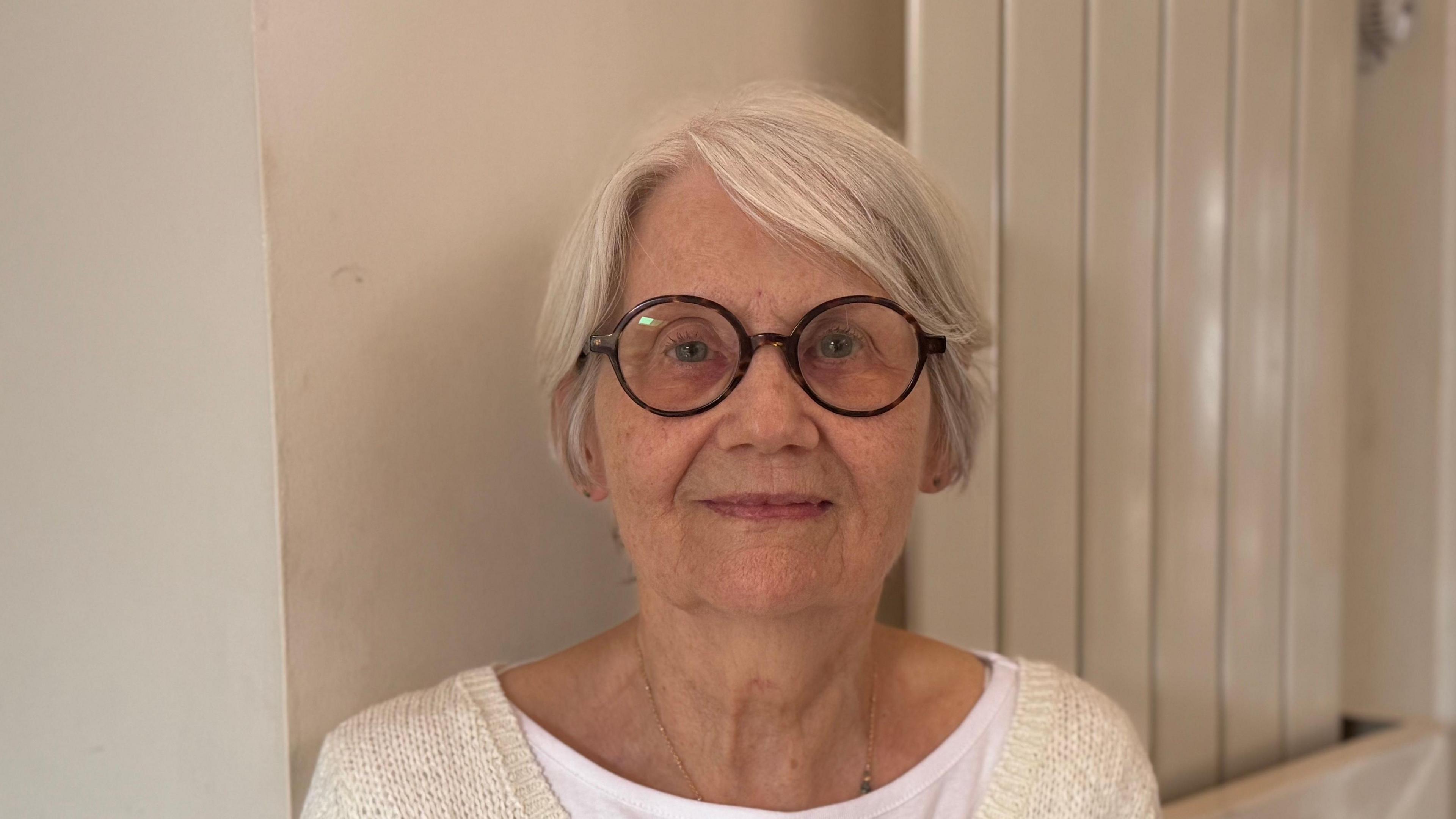 A head and shoulders image of Fran Tuck. She is wearing glasses and a cream cardigan over a white T-shirt. She is looking into the camera.