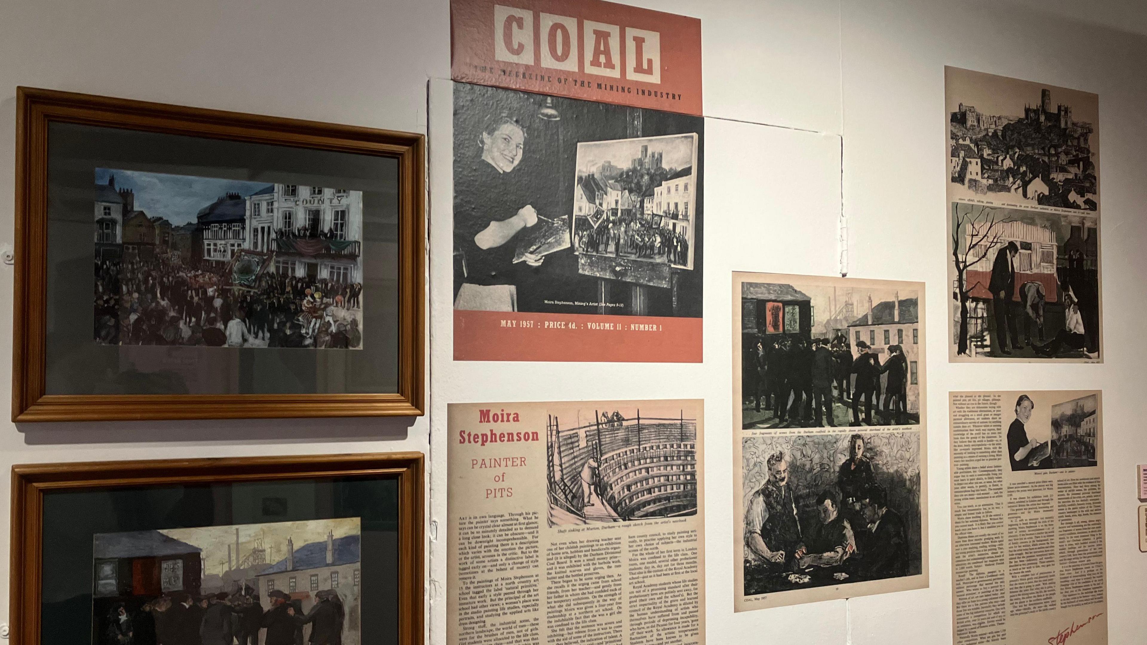 Two paintings are framed on a wall. They depict mining scenes. Next to them hang newspaper articles featuring Moira Stephenson, an illustrator for Coal Magazine.