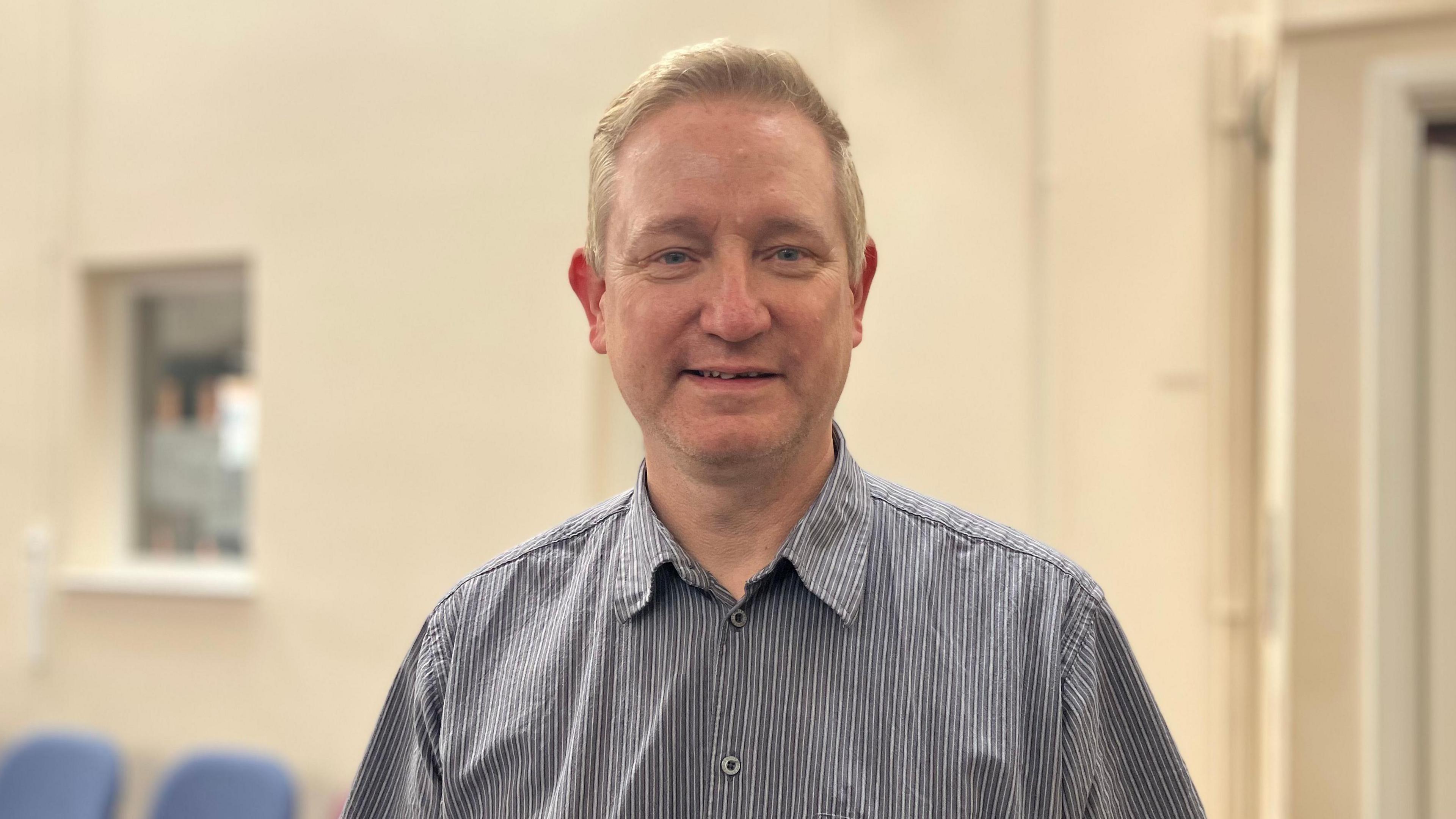 Man in striped shirt standing in school.
