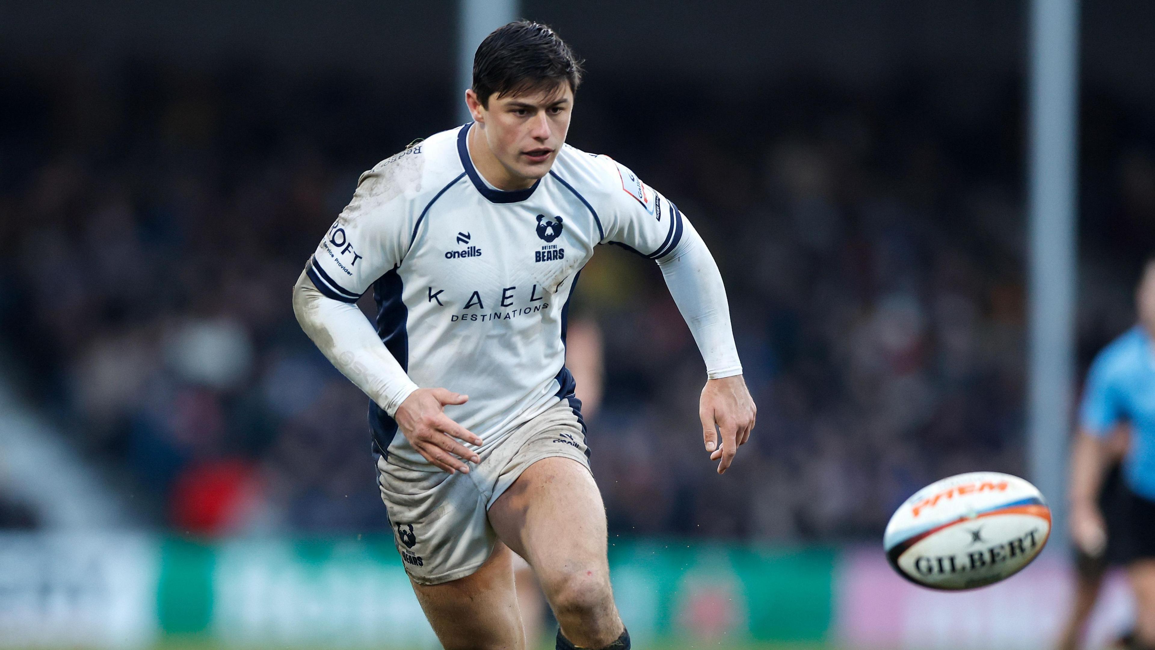 Louis Rees-Zammit running on the pitch during a game for Bristol with the ball in the air in front of him
