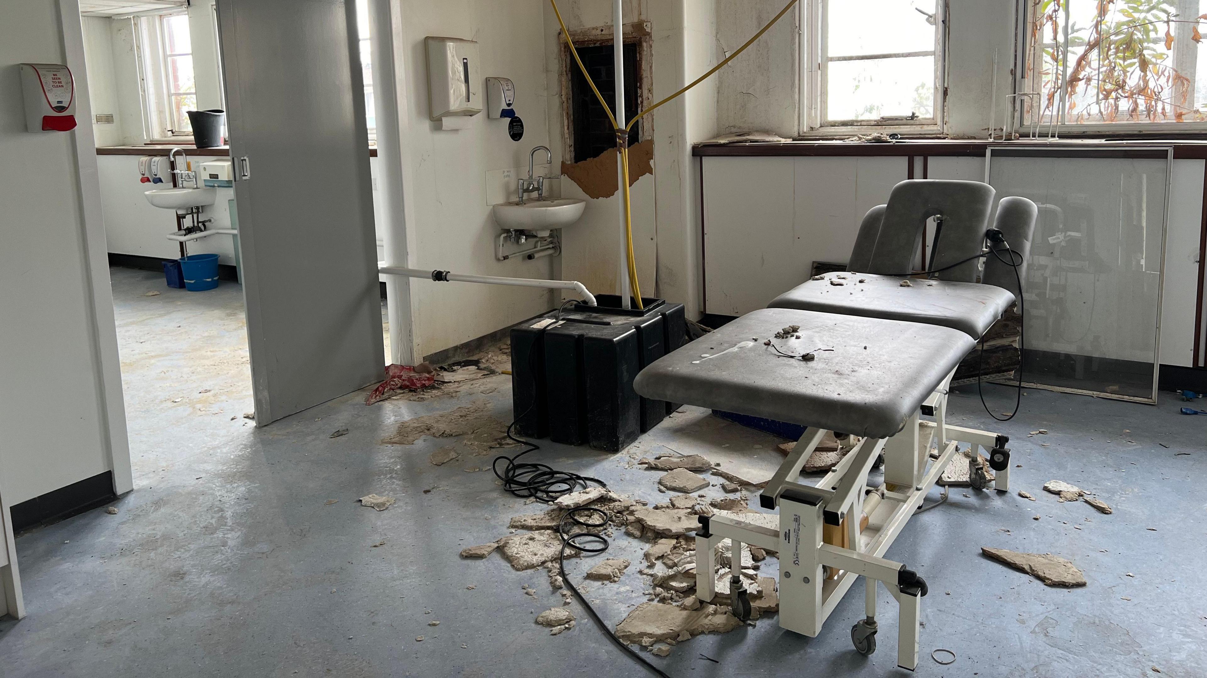 Crumbled plaster litters the floor of a hospital room.