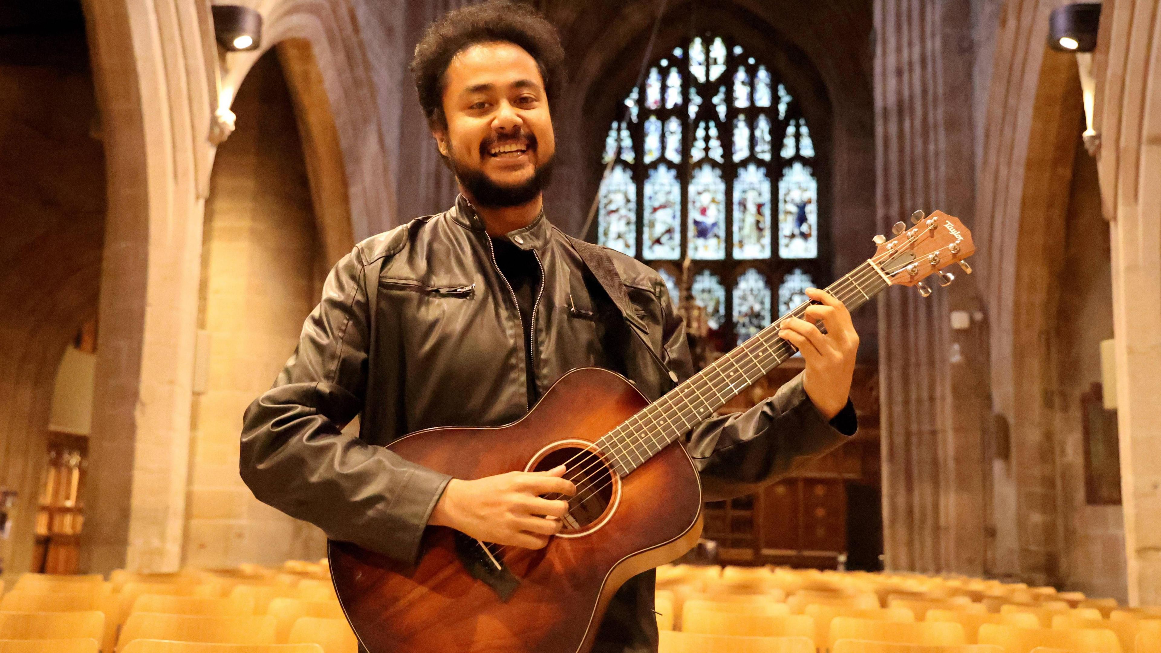 A man smiling holding a guitar 