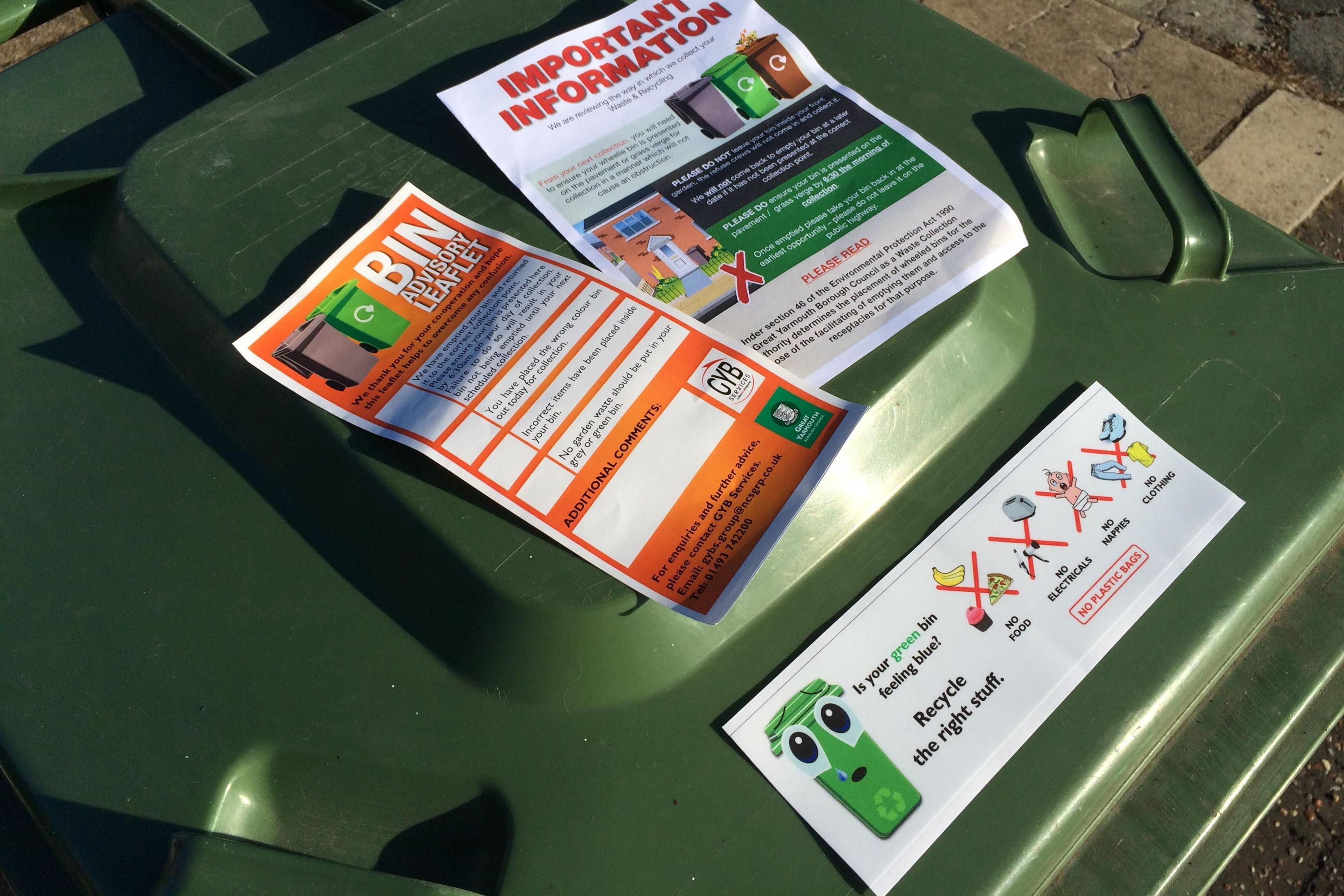 A bin with a sticker and leaflets explaining what can be recycled