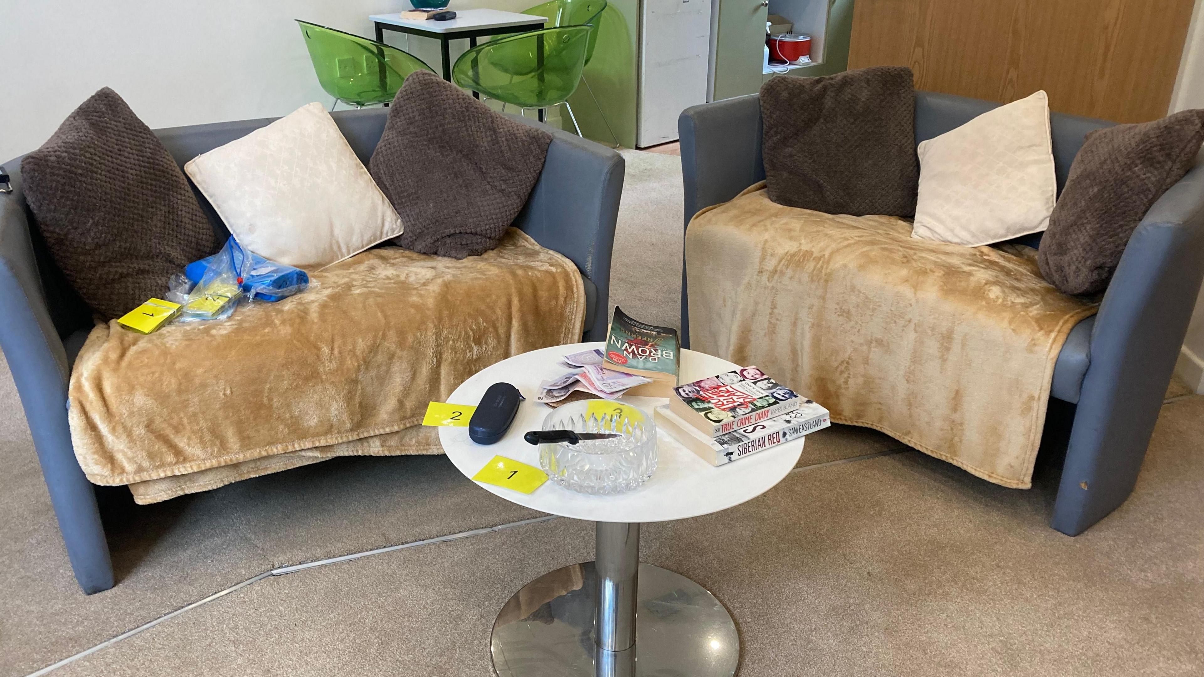 Two sofas and a coffee table, set up with fake evidence for a simulated crime scene as part of the students' criminology course.